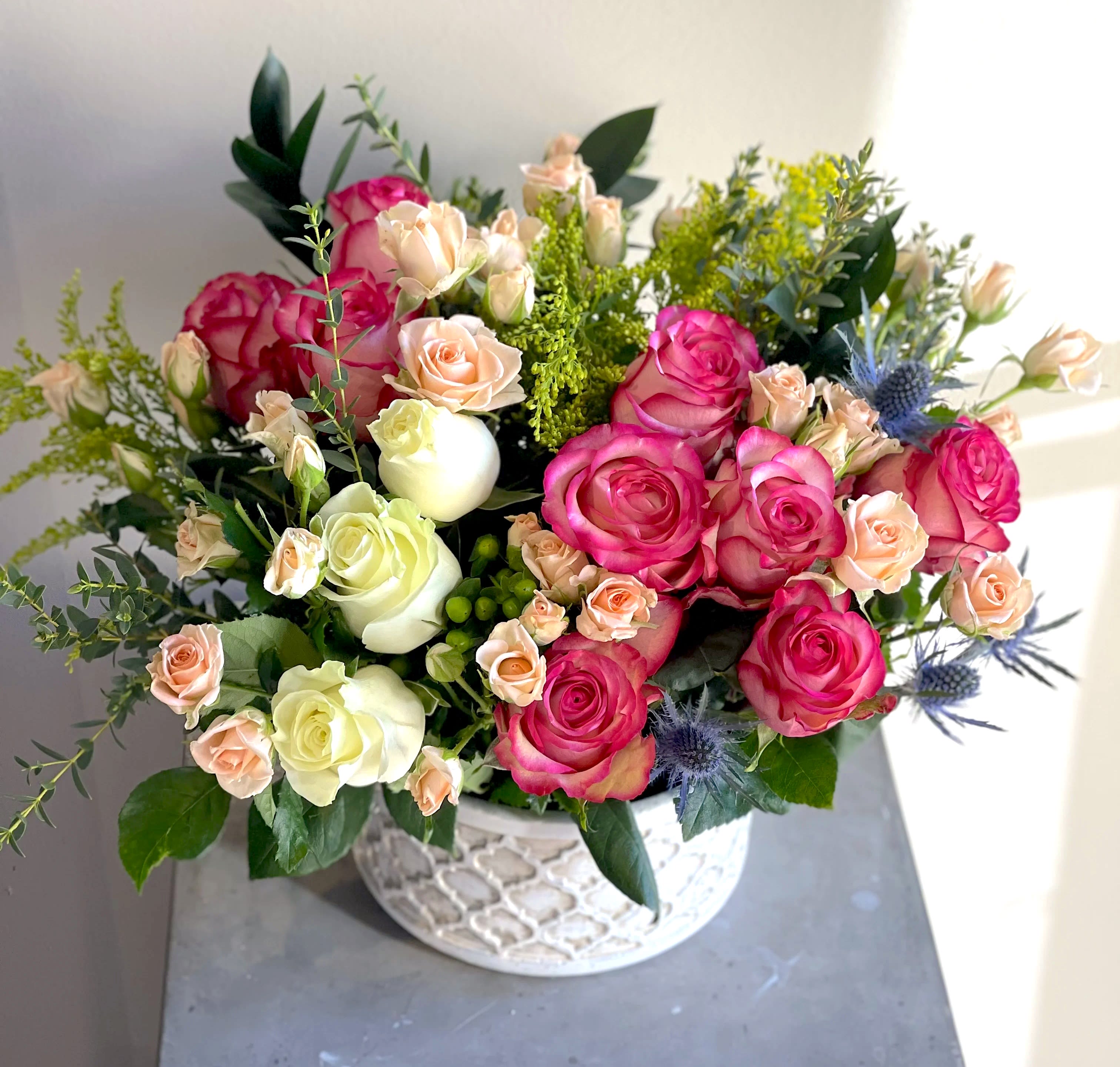 Pink and cream roses arranged in a white patterned bowl