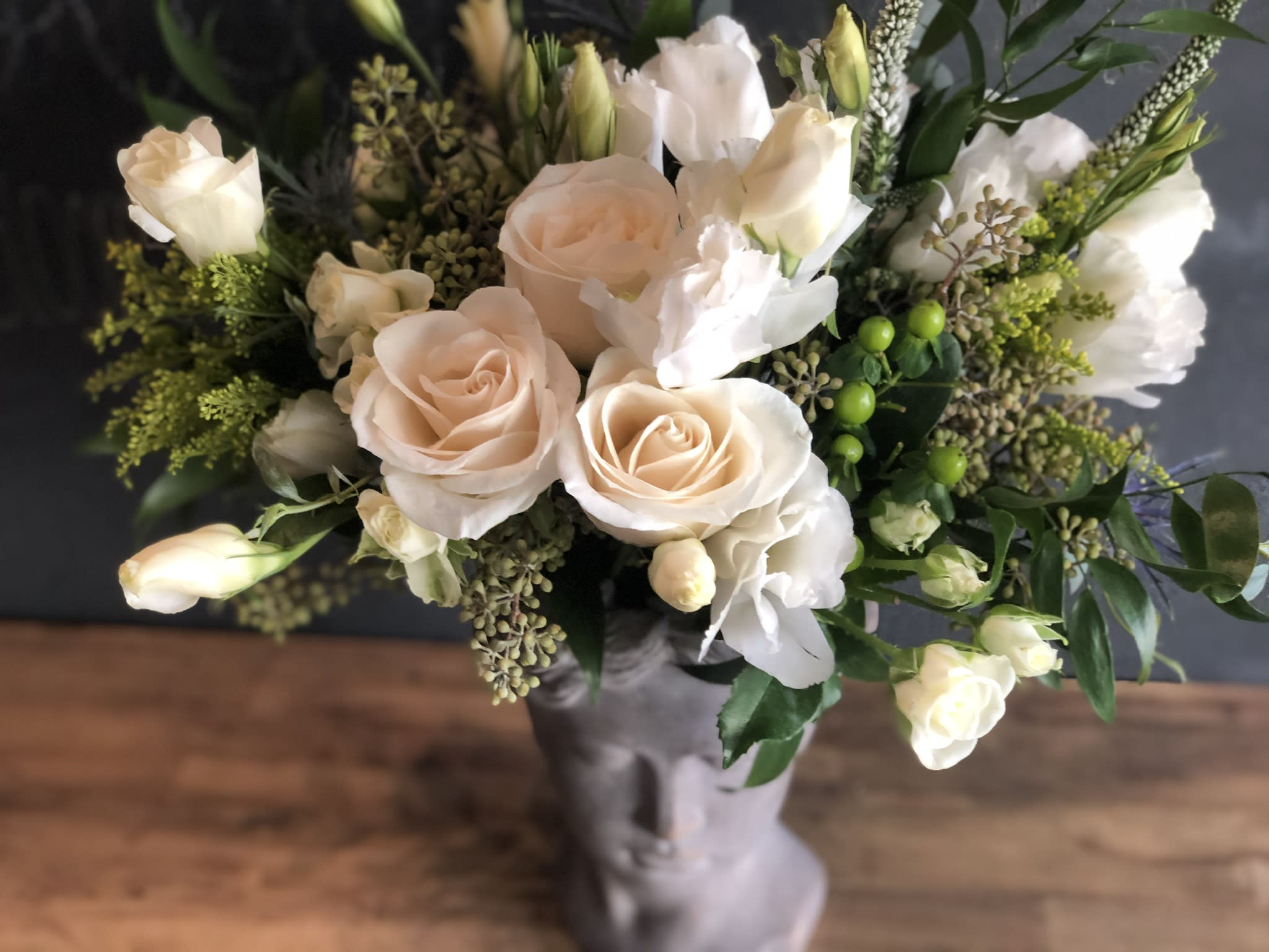 Bouquet of pale peach roses and white blooms in a gray vase