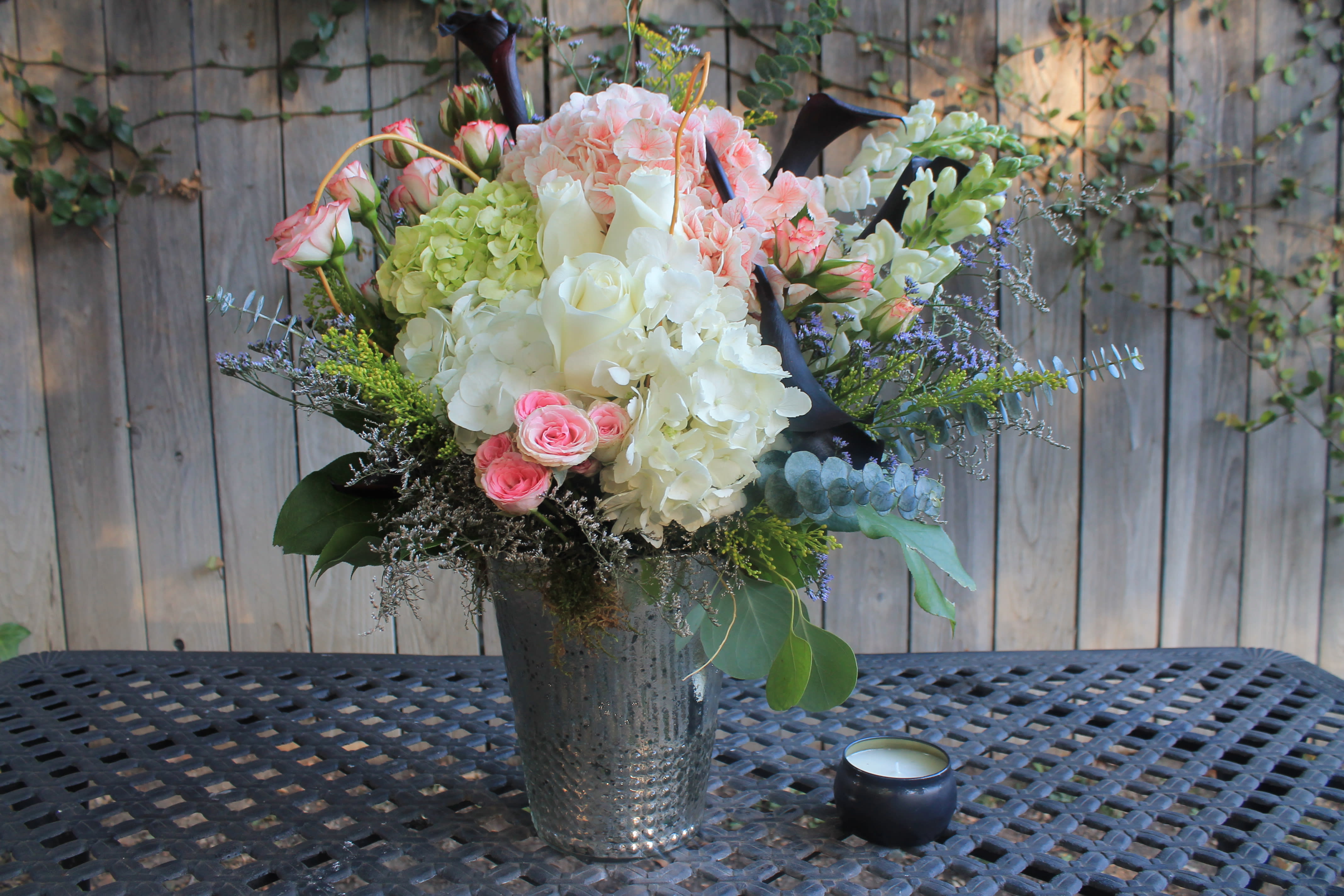 Mixed bouquet of pink, white, and green flowers in a metal vase