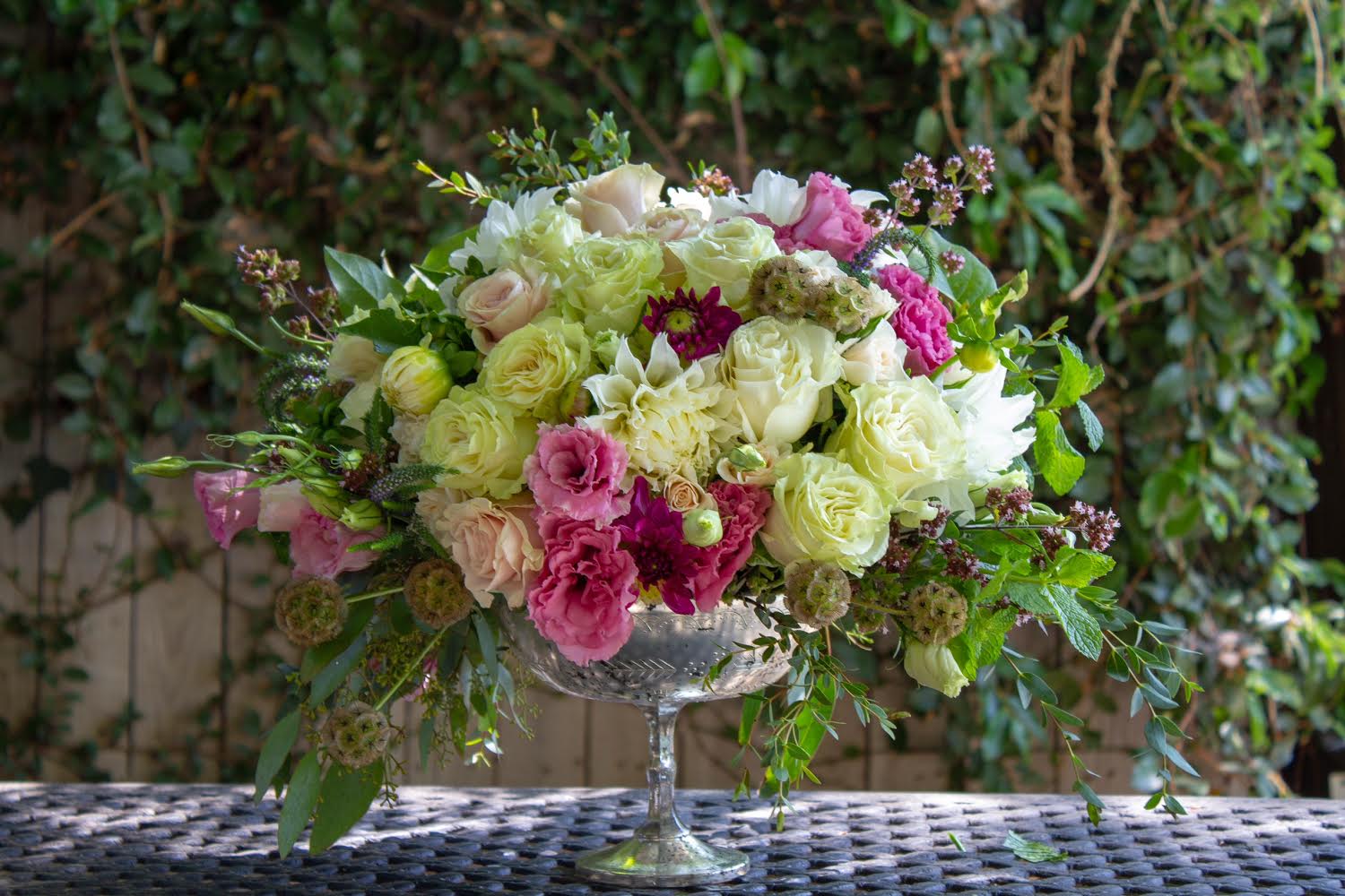Mixed pink and white floral arrangement in a silver pedestal vase