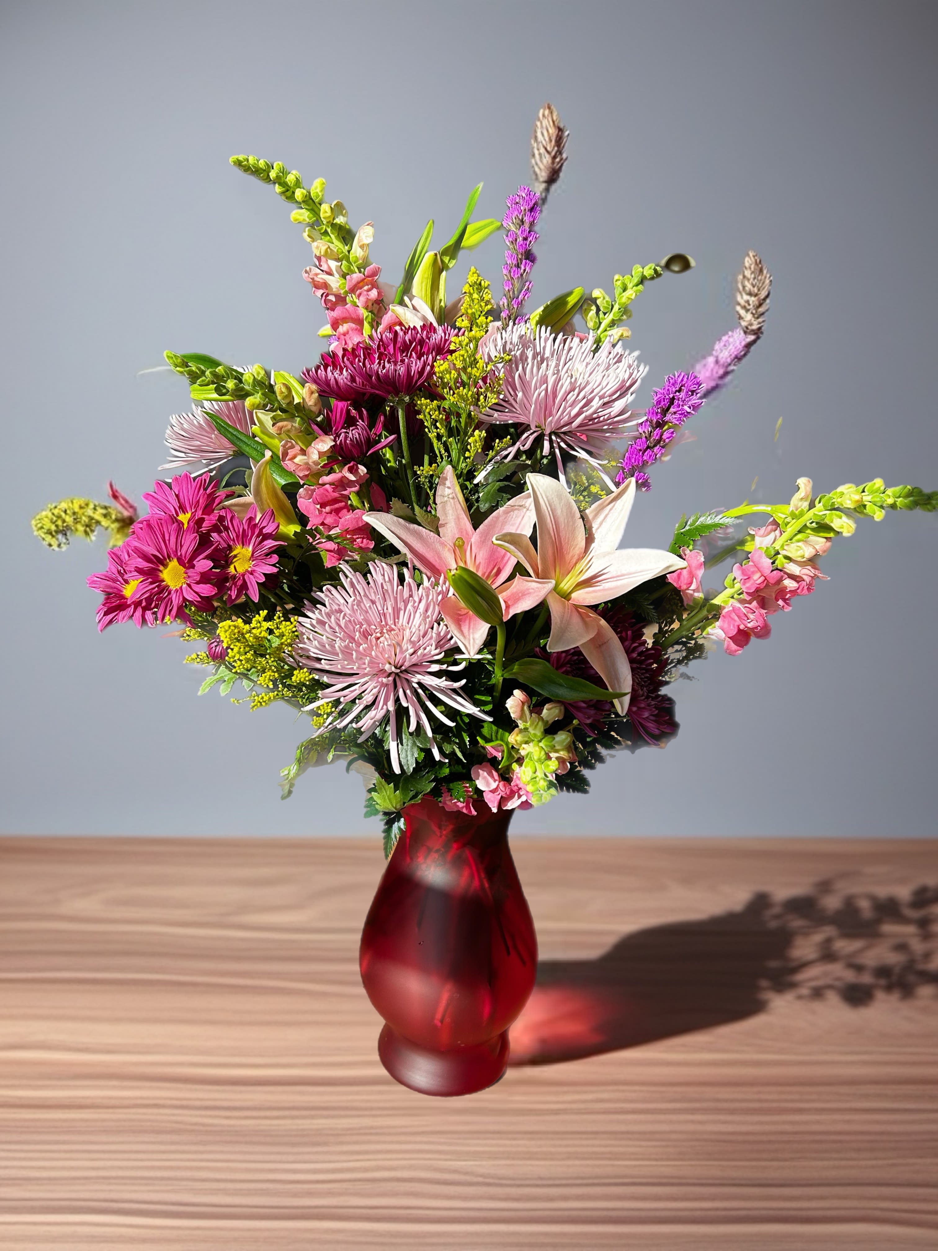 Mixed bouquet with lilies and pink chrysanthemums in a red vase