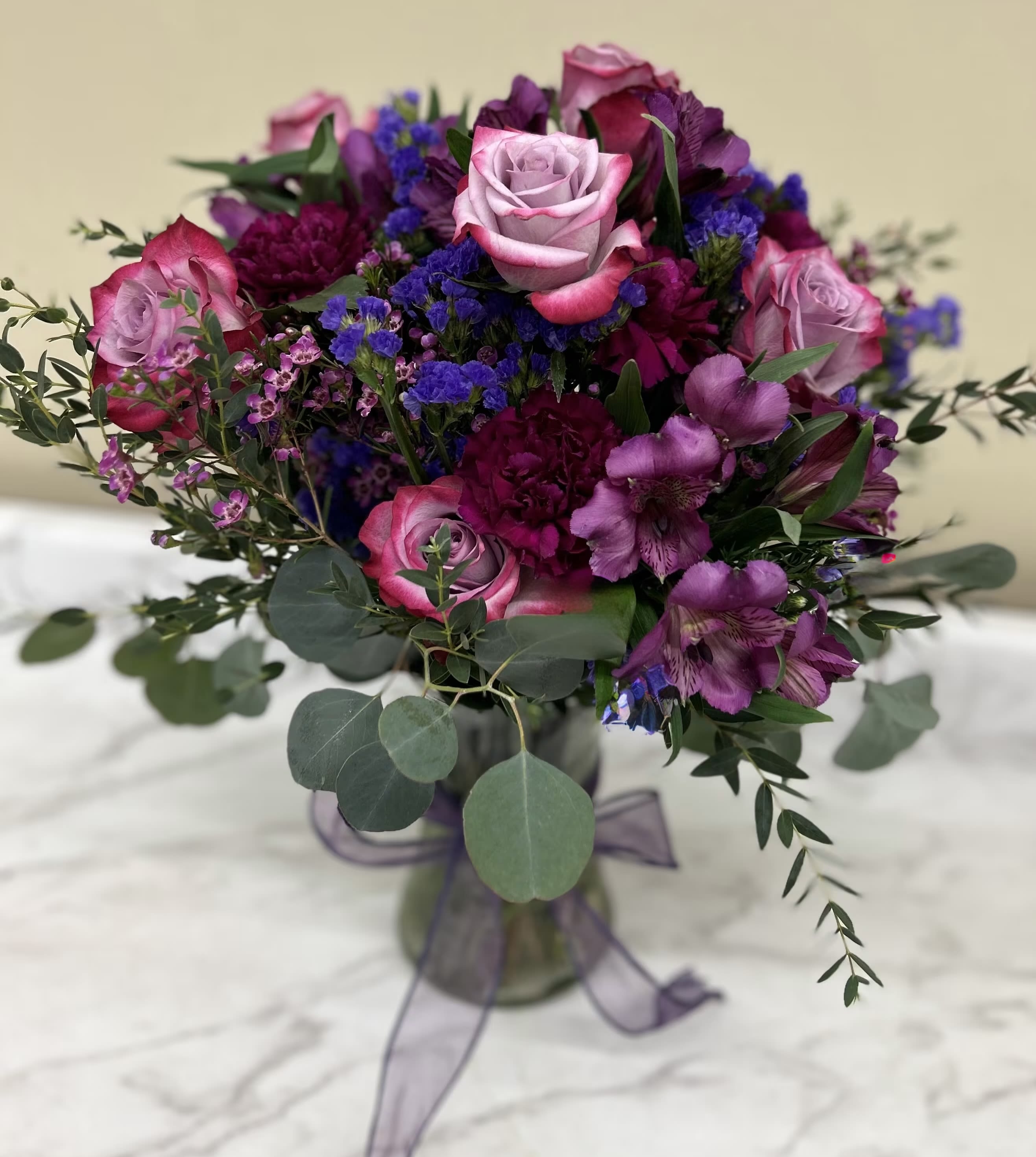 Bouquet of pink roses and purple flowers in a glass vase