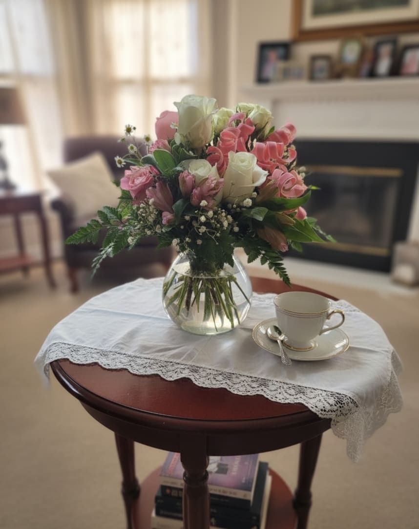 Pink and white rose bouquet in a clear glass vase on a table