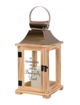 Wooden memorial lantern with metal top, glass panels, and candle inside.