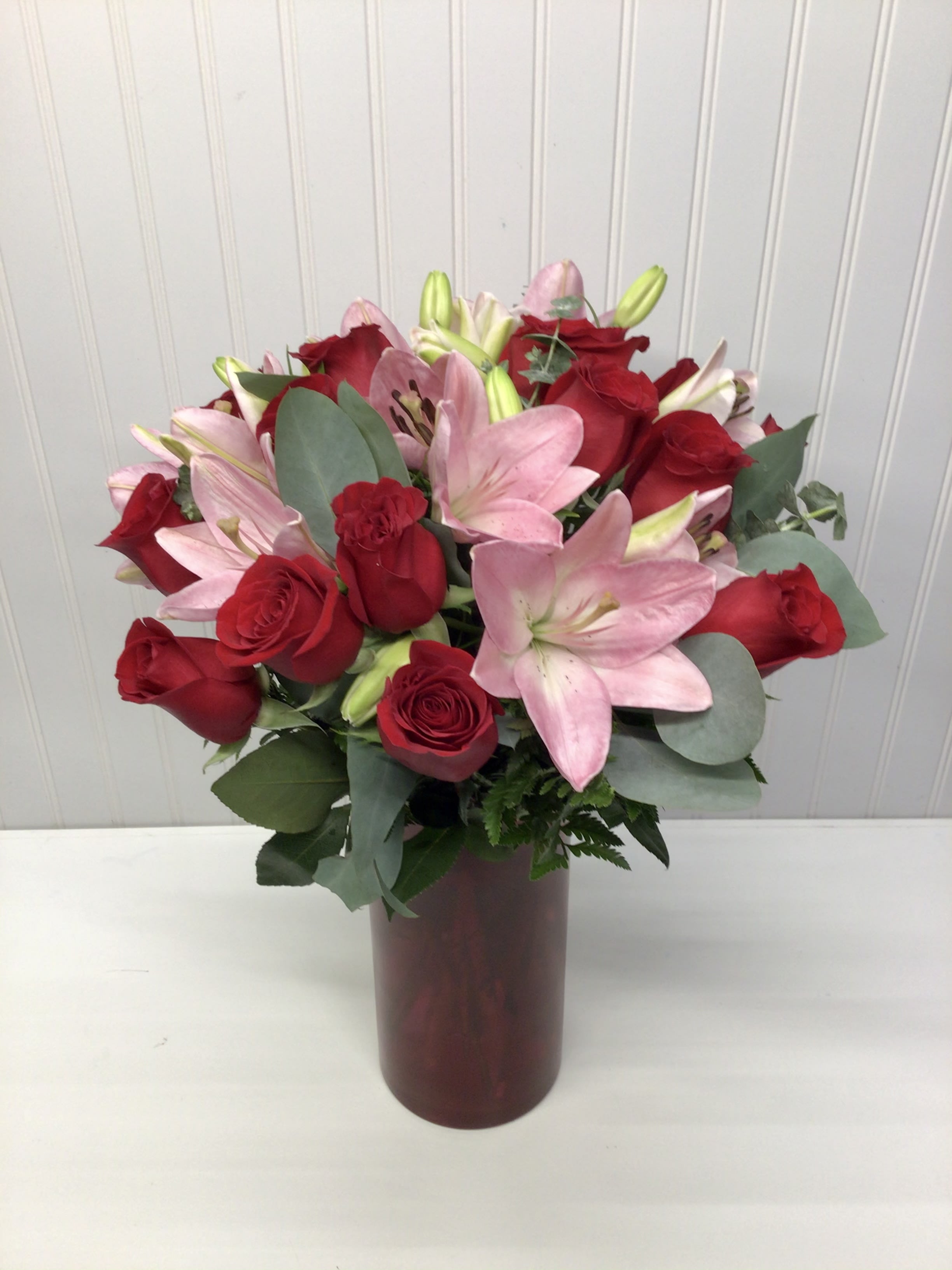 Tall red vase arrangement of red roses and pink lilies