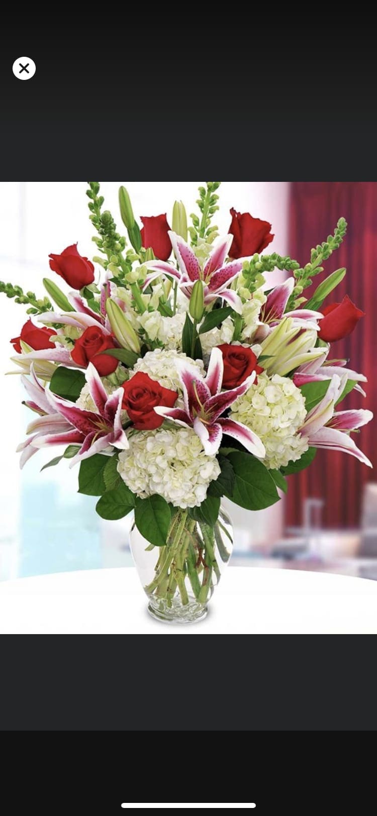 Bouquet of red roses, pink lilies, and white hydrangeas in a glass vase