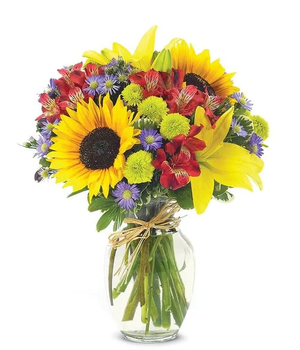 Bright mixed bouquet with sunflowers, lilies, and daisies in a glass vase