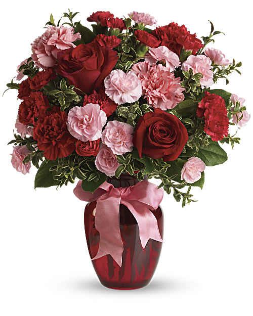 Red roses and pink carnations in a red vase with a pink ribbon