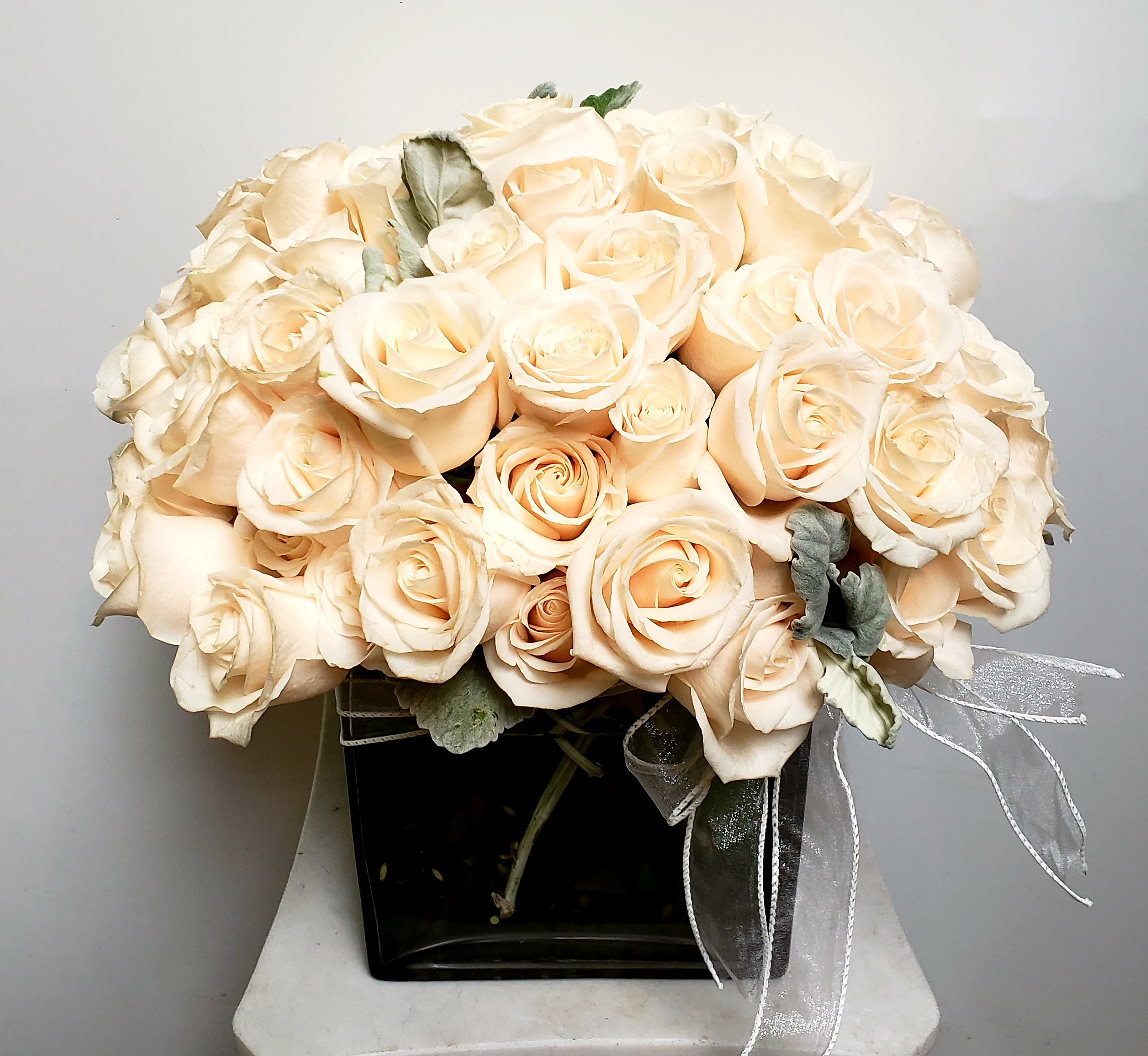 Bouquet of pale peach roses in a black vase with a sheer ribbon