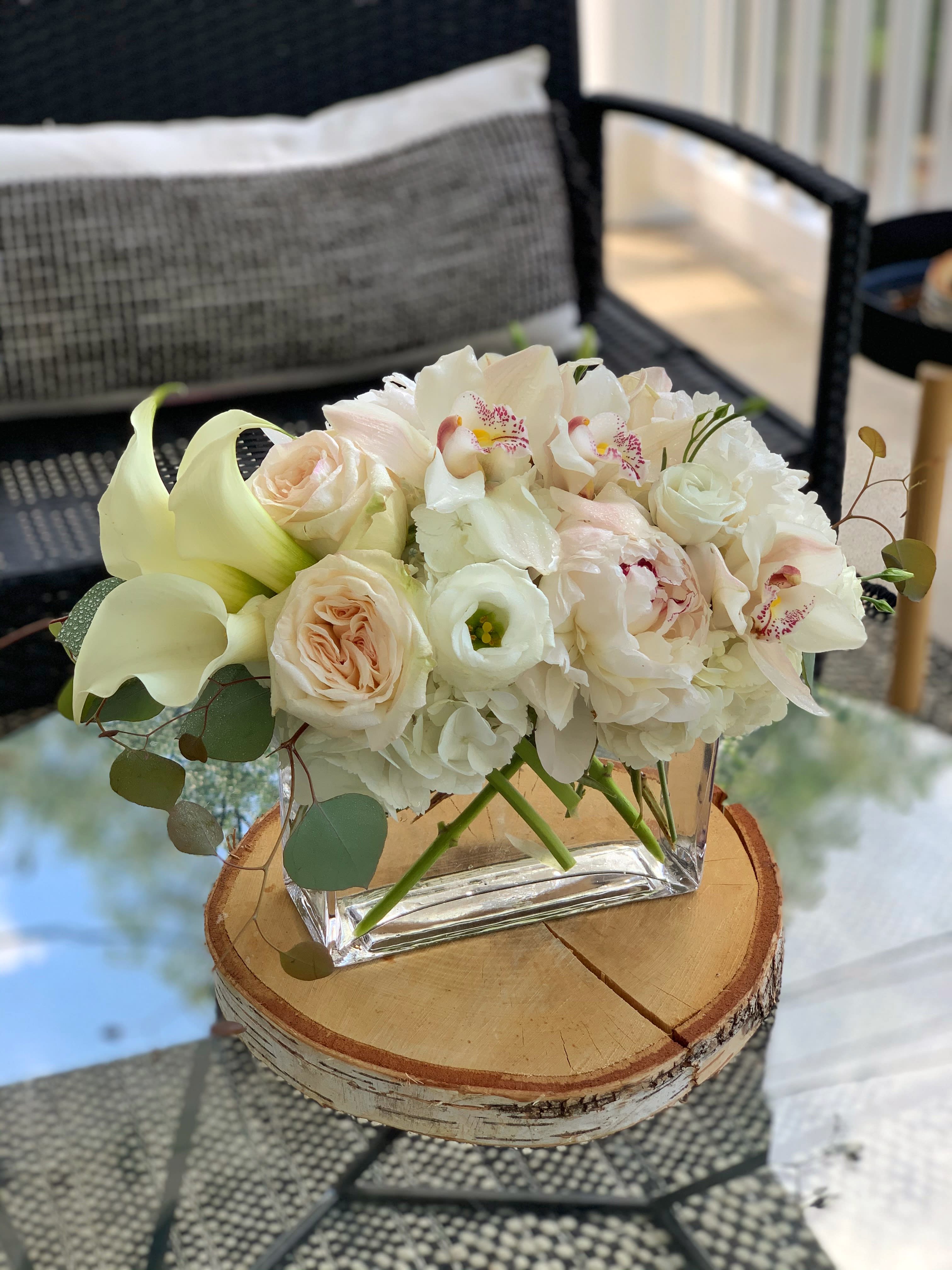 White and blush floral arrangement in a clear square vase