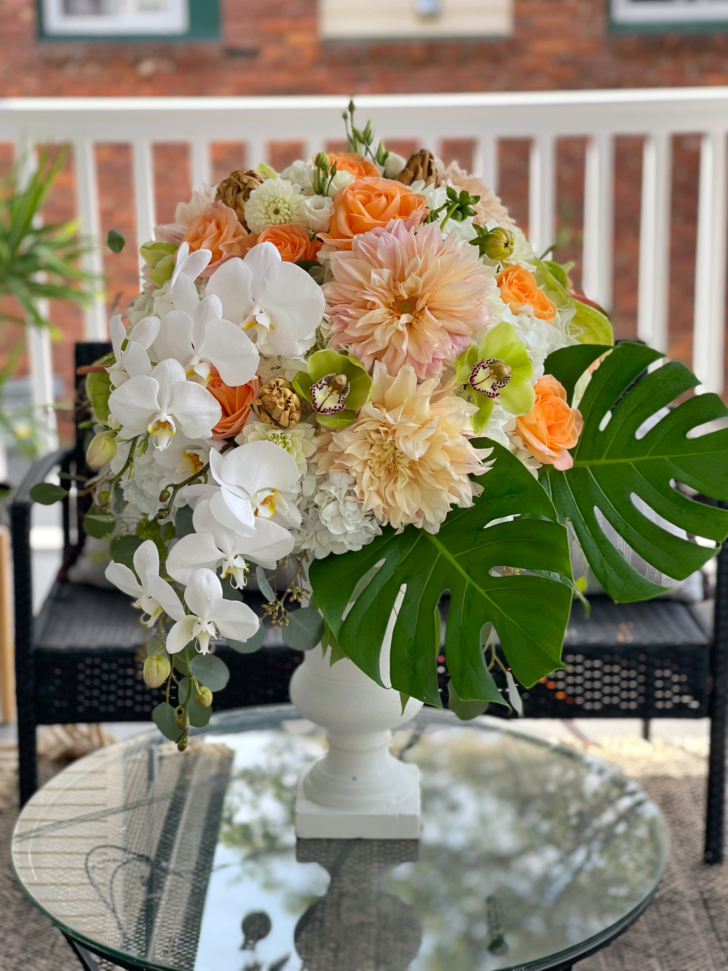White and peach floral arrangement in a white pedestal vase