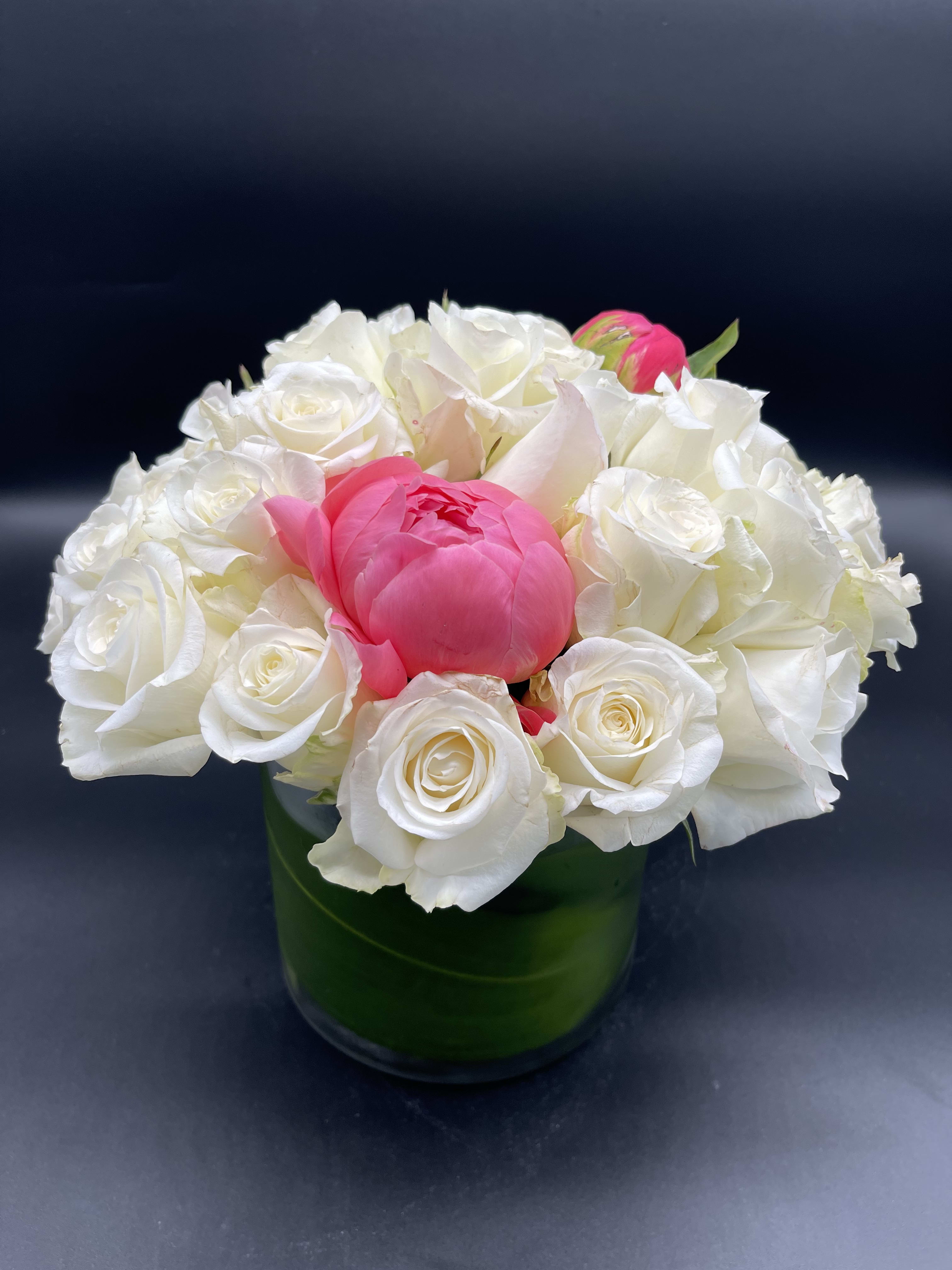 White roses and a pink peony in a green glass vase