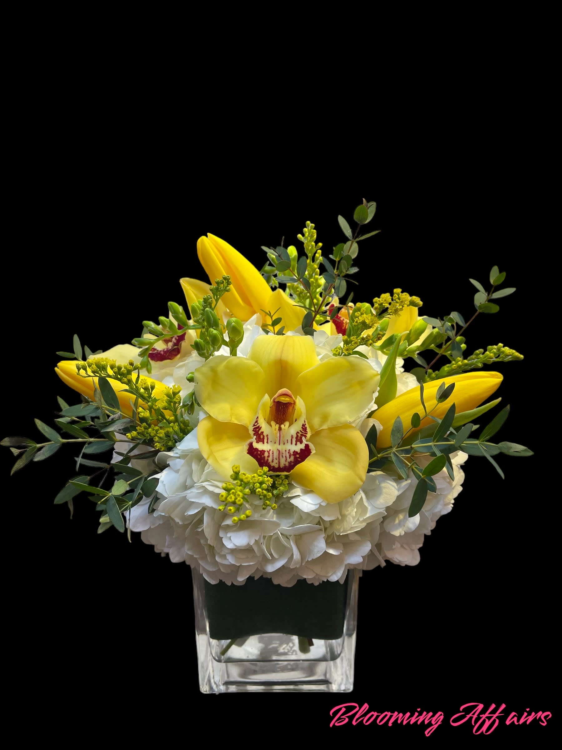 Yellow orchids and white hydrangeas in a clear square vase
