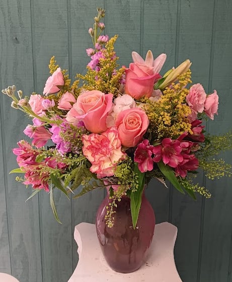 Pink roses and mixed flowers arranged in a purple vase