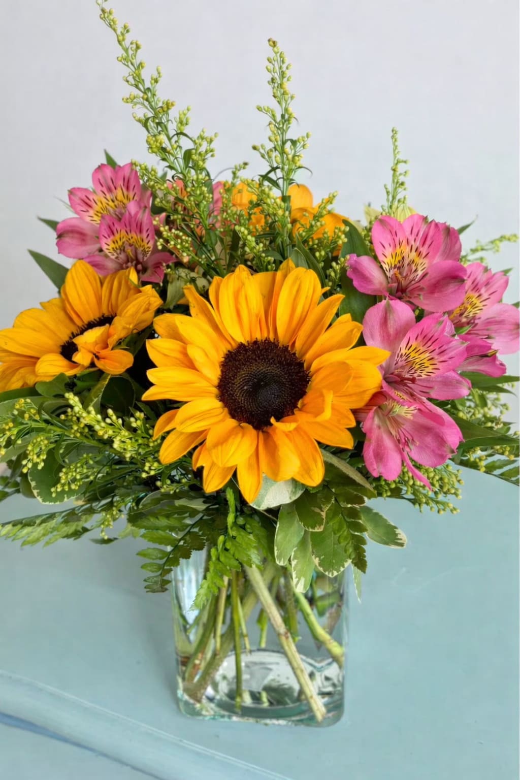 Bouquet of yellow sunflowers and pink alstroemeria in a glass vase
