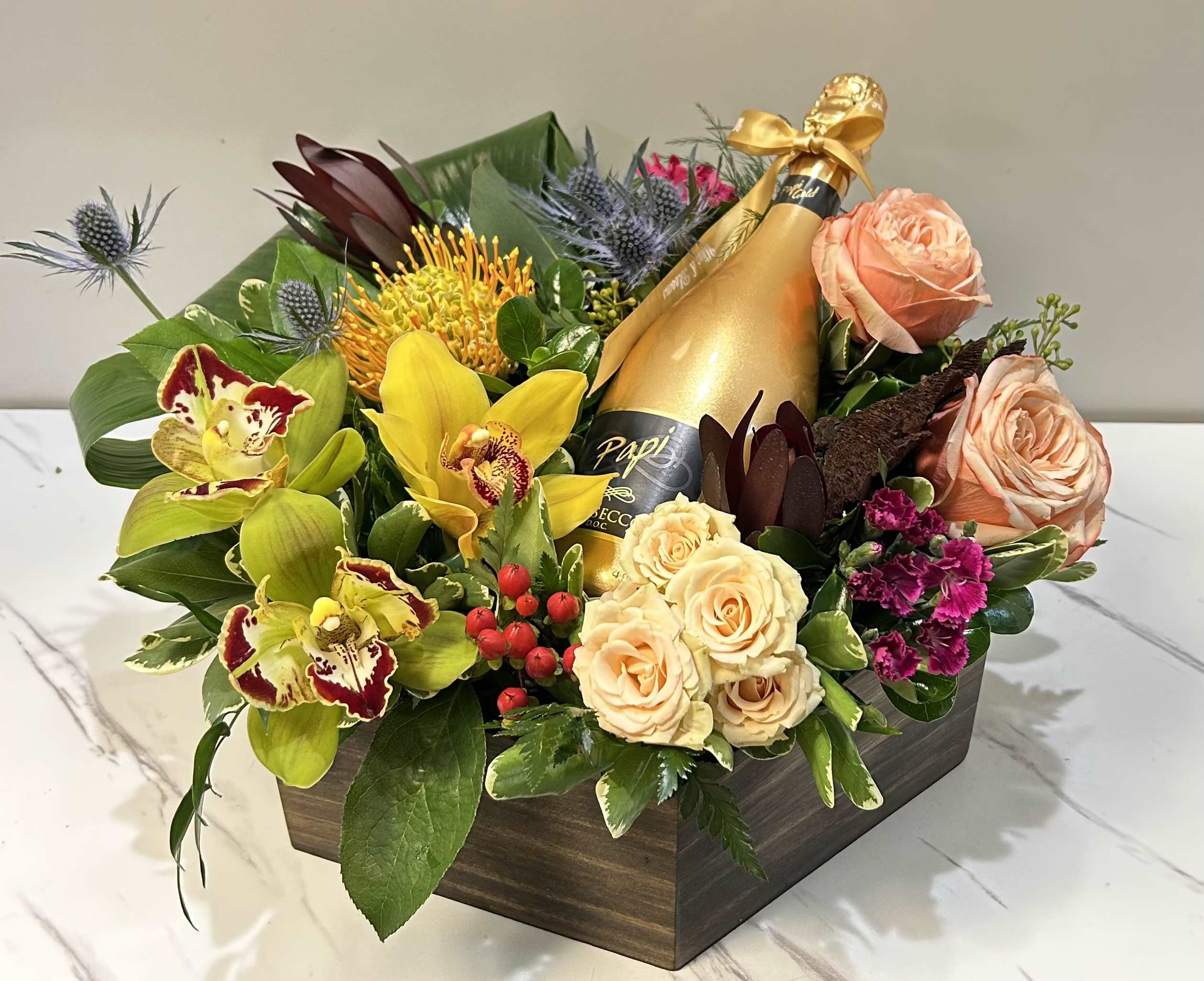 Mixed floral arrangement with a champagne bottle in a wooden box