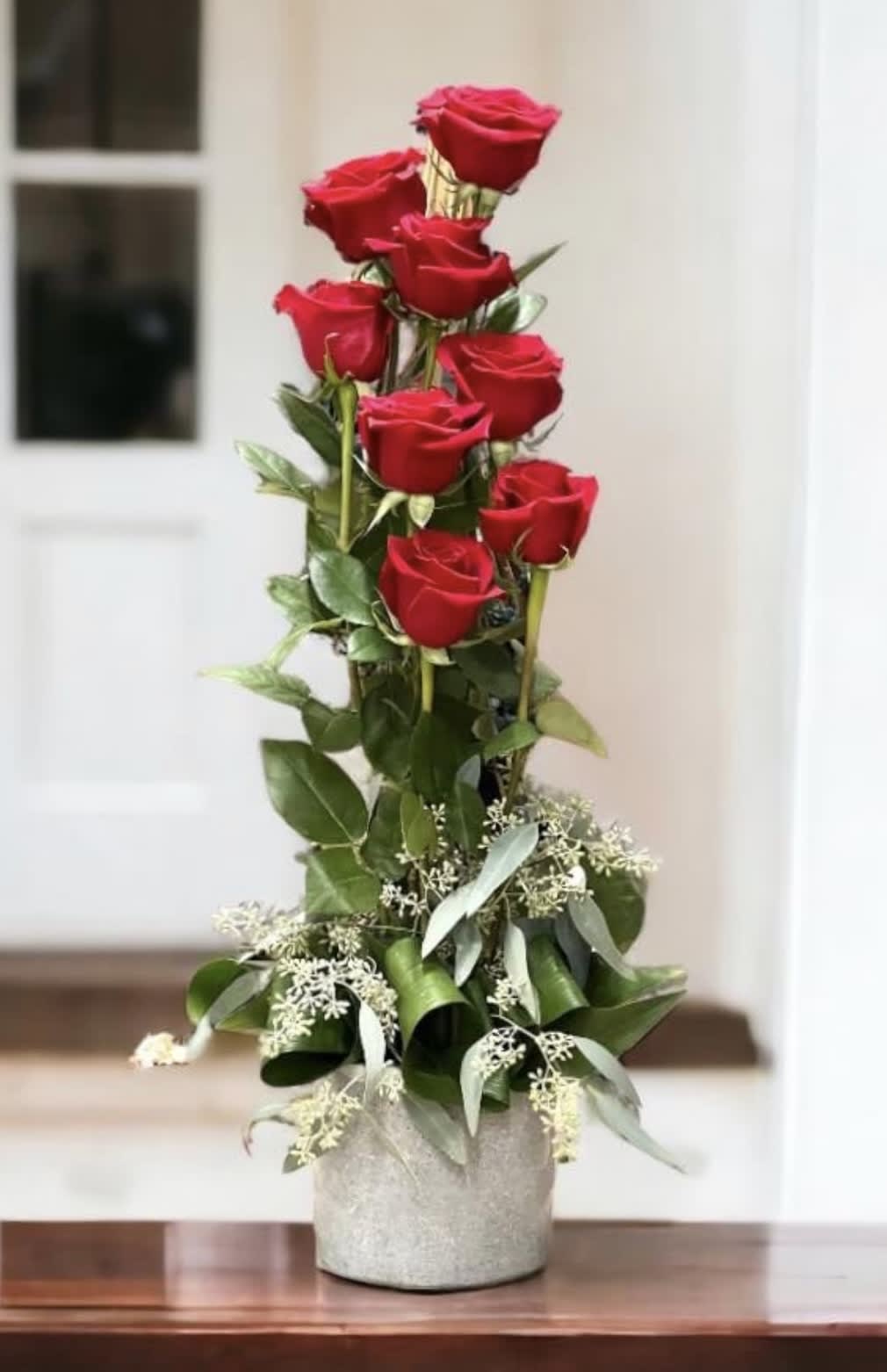 Tall arrangement of red roses in a silver vase