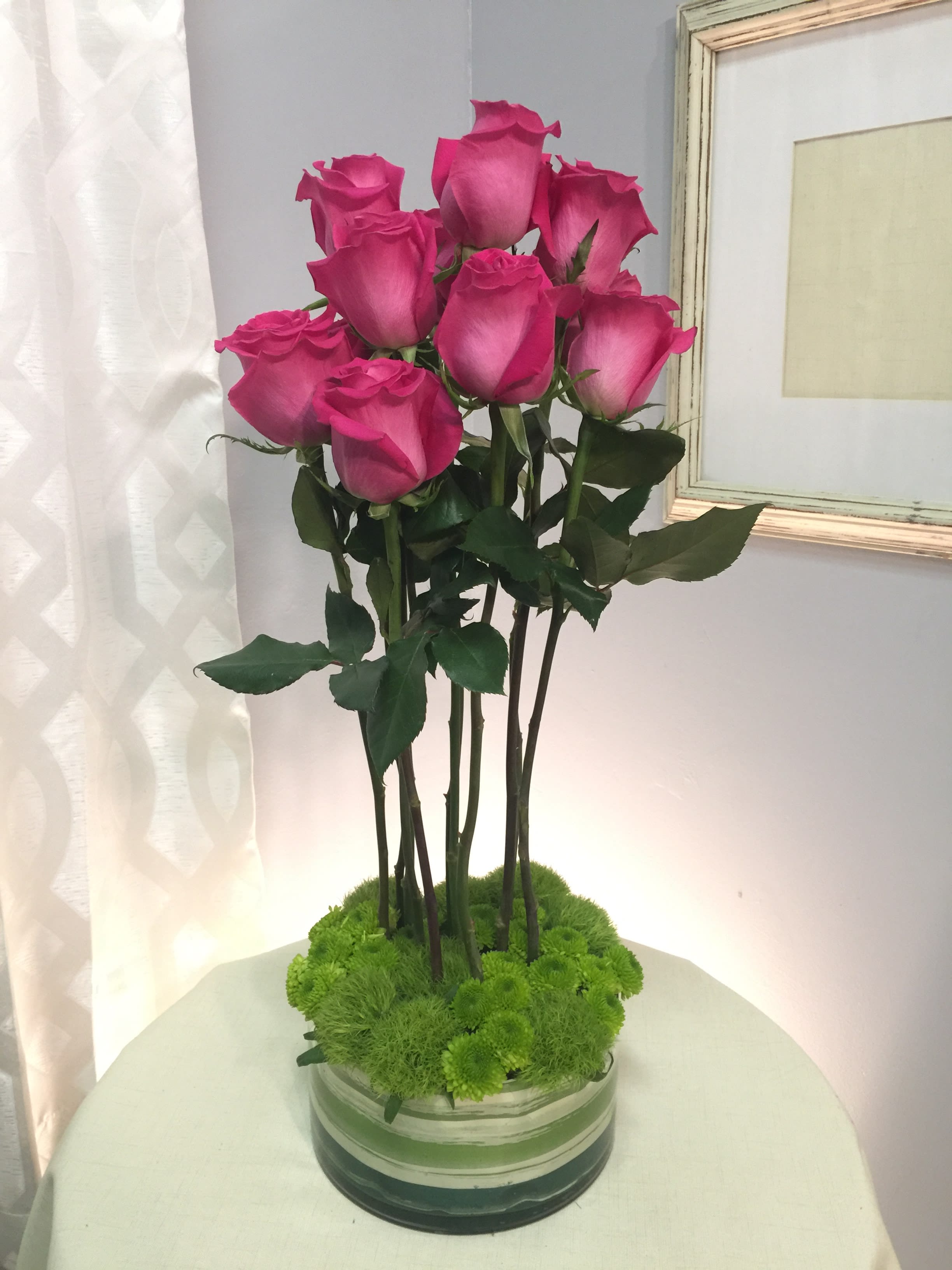 Pink roses arranged in a low glass vase with green moss