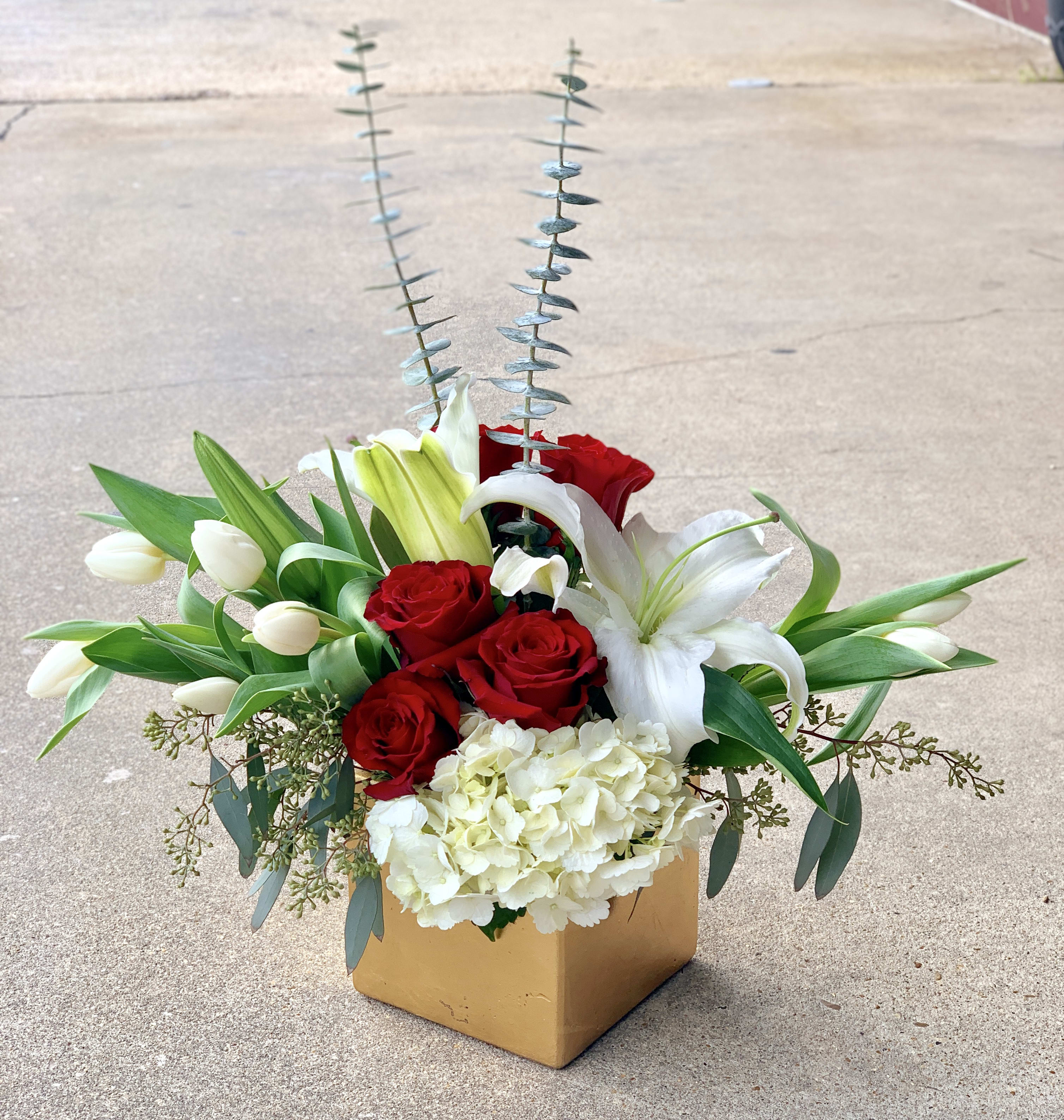 Red roses and white lilies in a square box with tall silver foliage