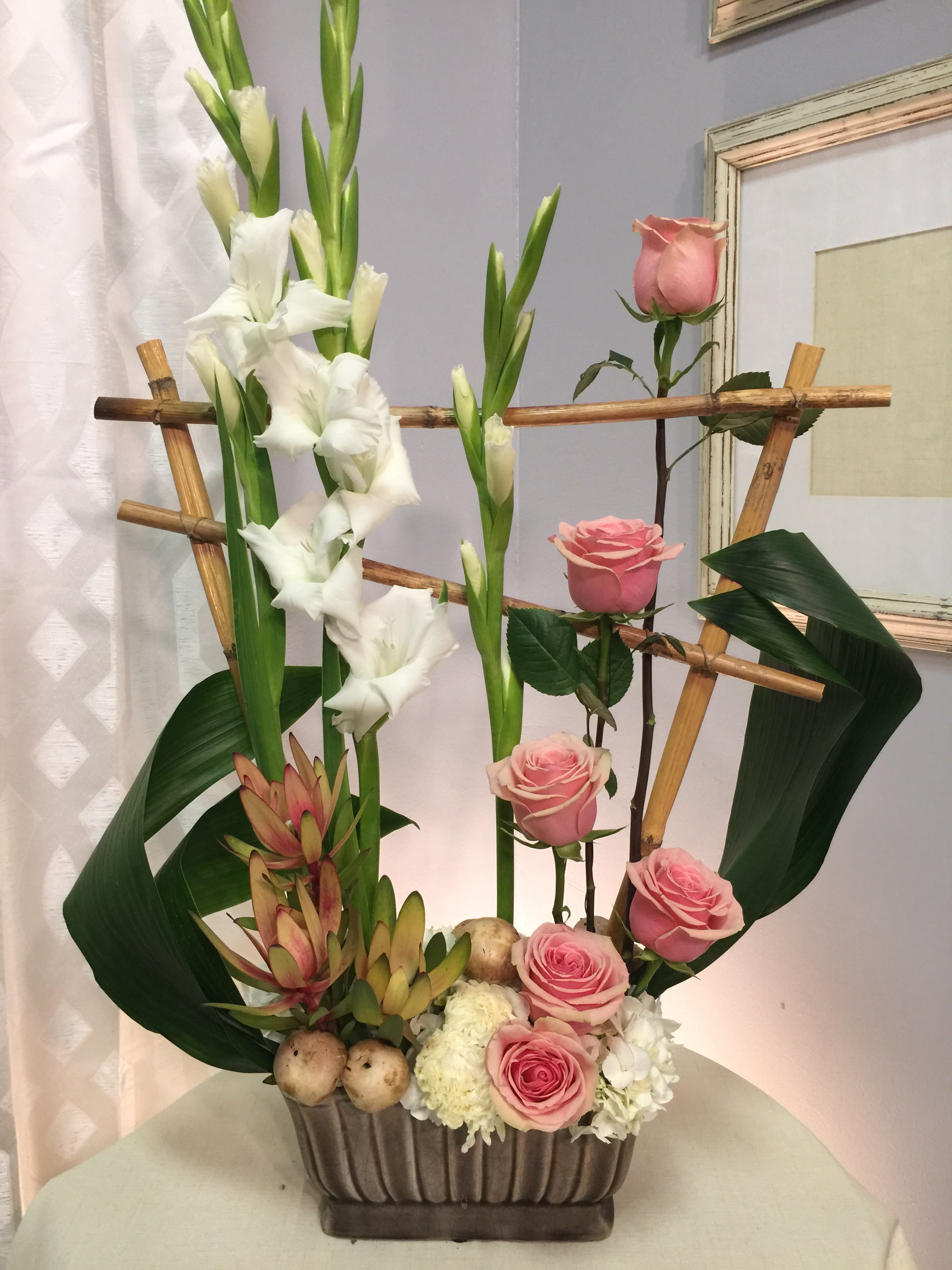 Tall floral arrangement with pink roses and white gladiolus in a rectangular vase