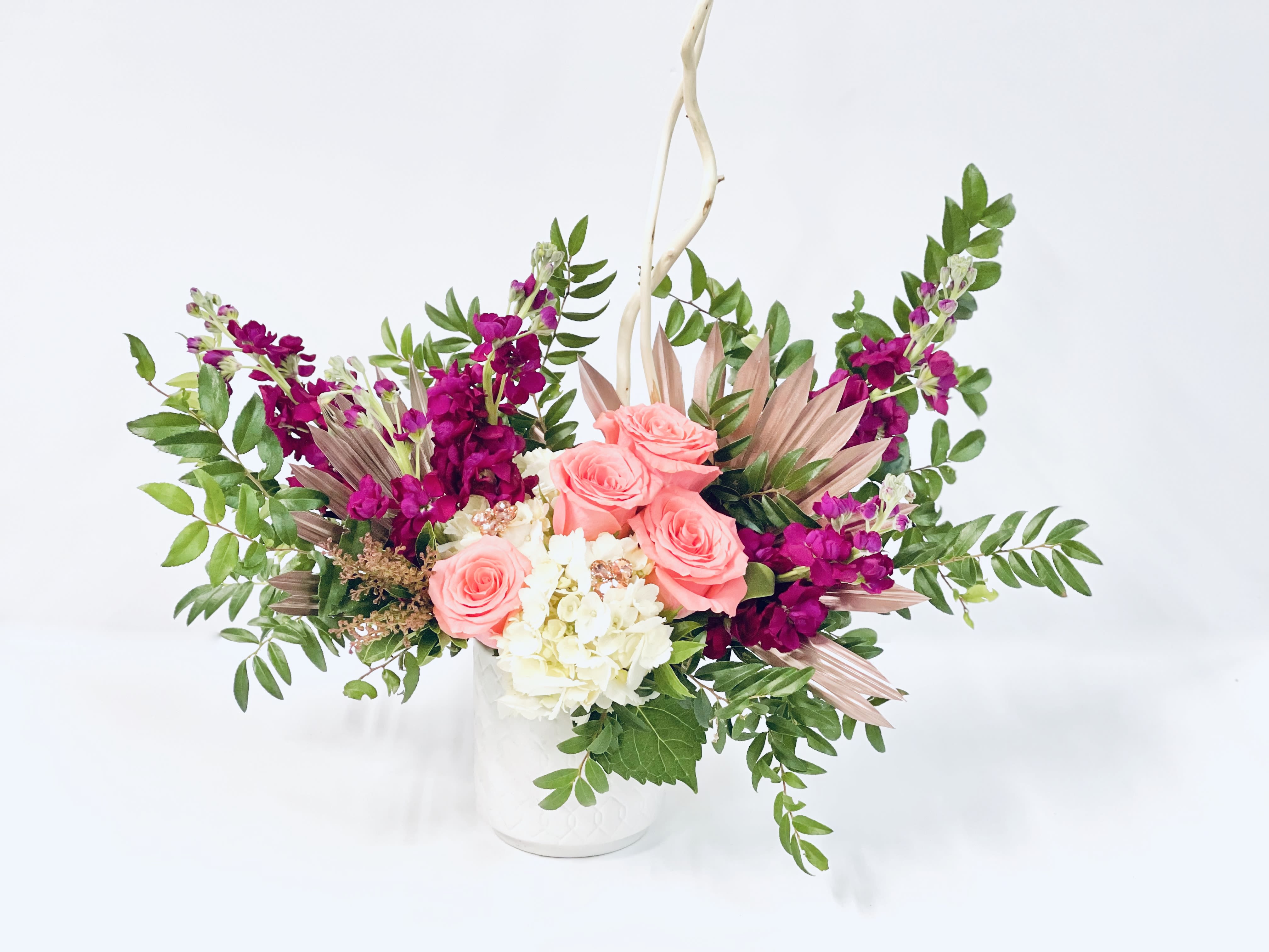 Pink roses and white hydrangea in a white vase with purple flowers