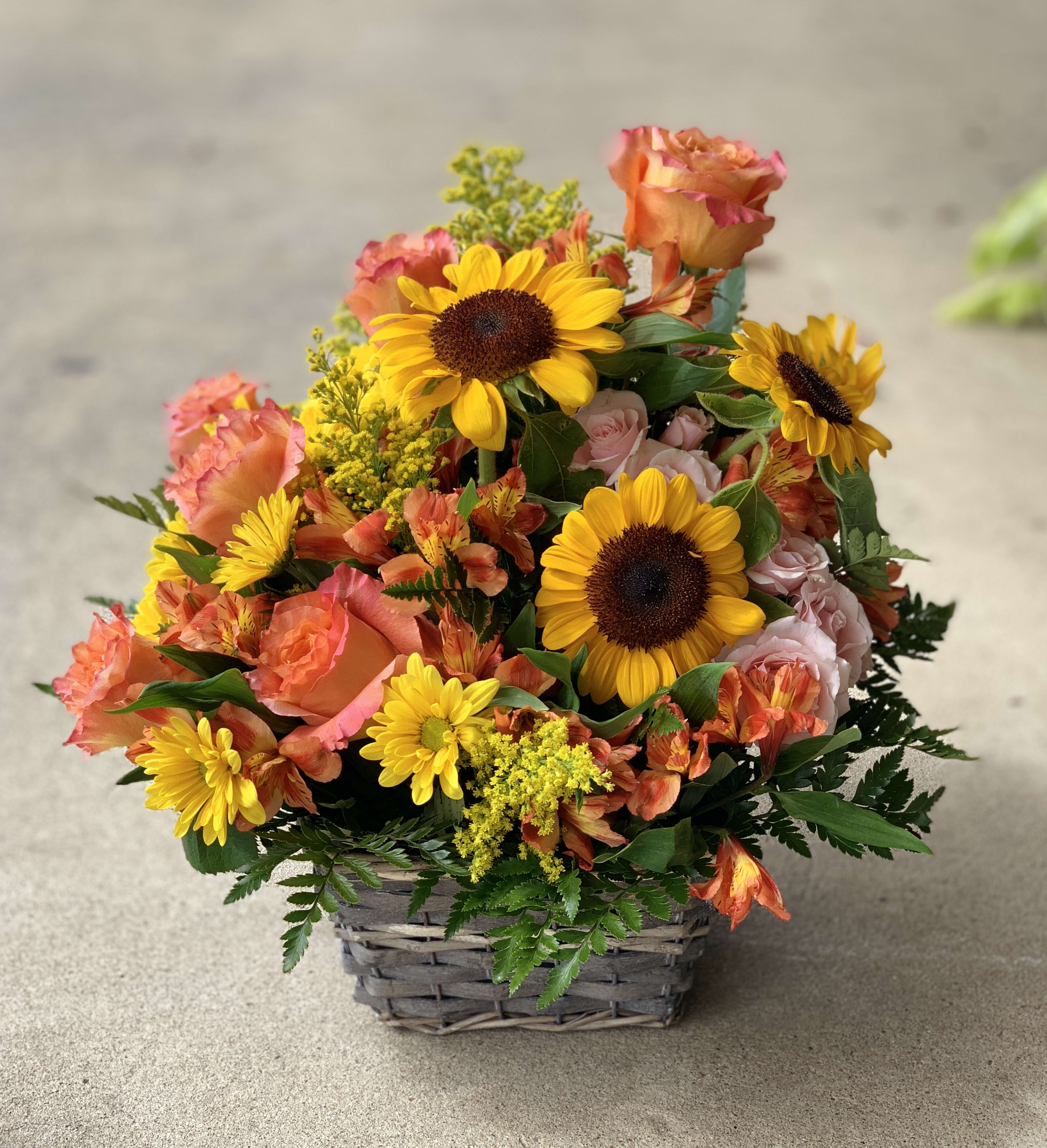 Basket of sunflowers, roses, and orange mixed blooms