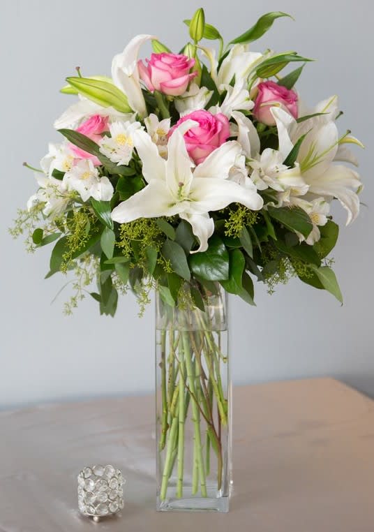 Pink roses and white lilies arranged in a tall glass vase