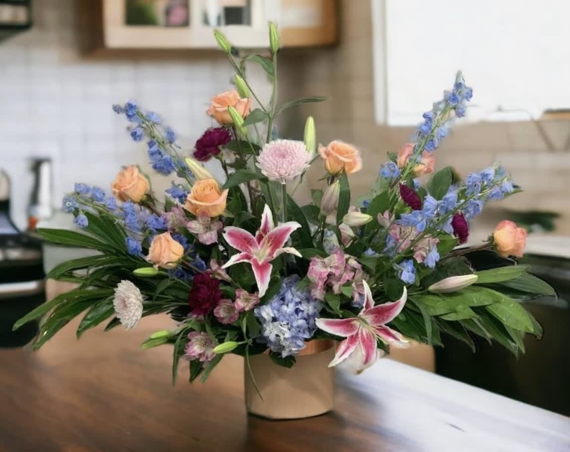 Mixed bouquet in a beige vase with pink lilies and peach roses
