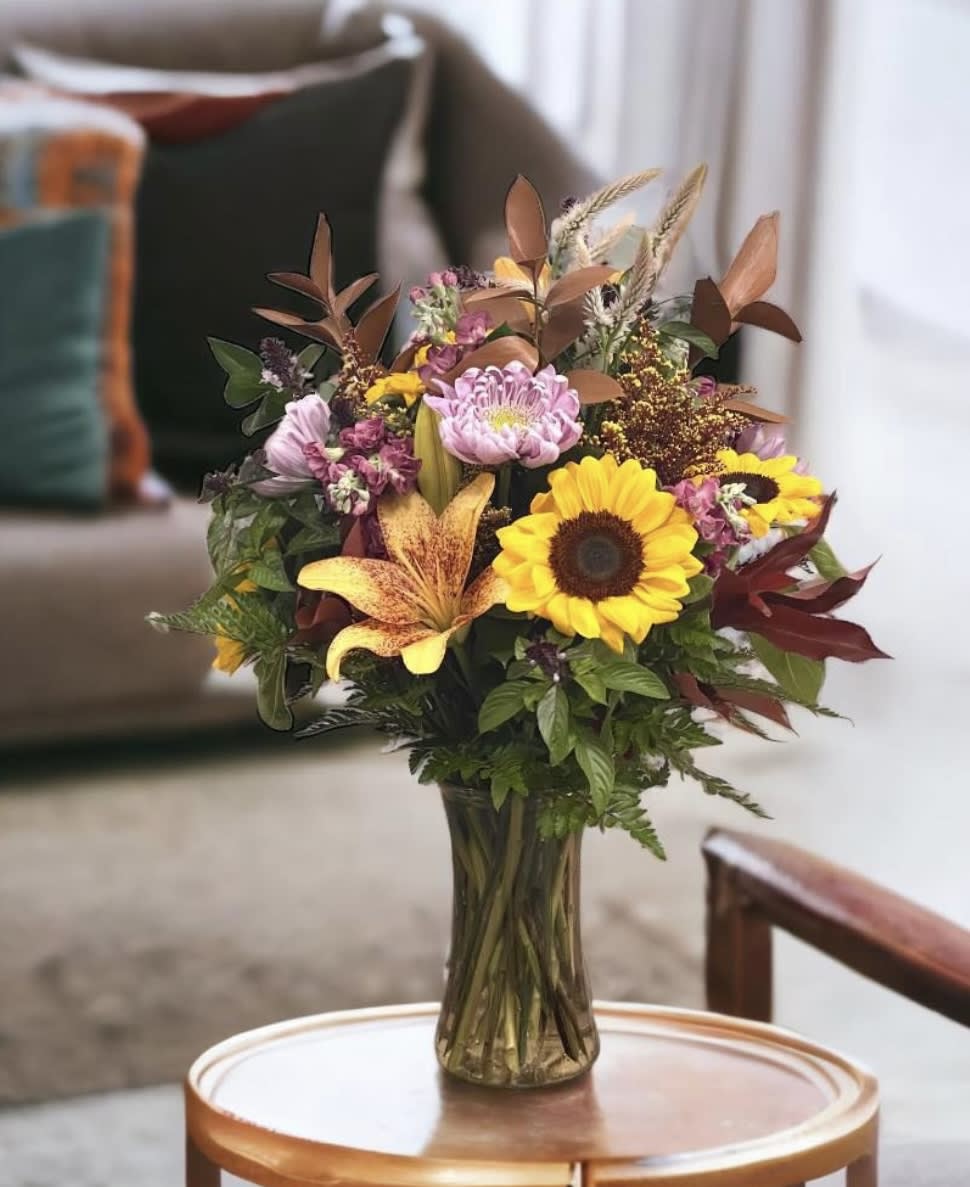 Bouquet of sunflowers, lilies, and mixed blooms in a glass vase
