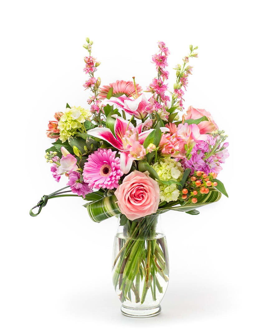 Mixed pink and peach flowers arranged in a clear glass vase