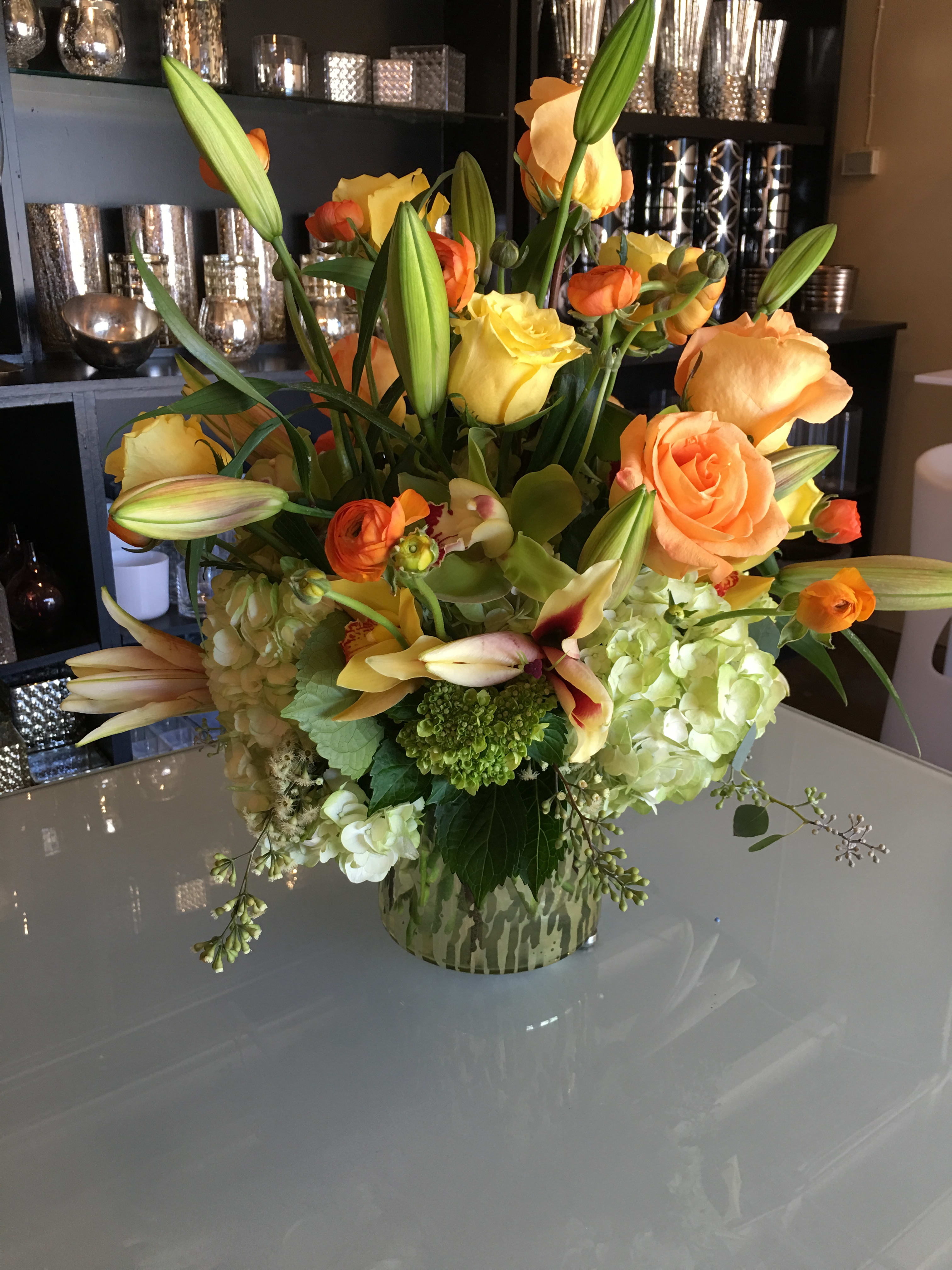 Mixed bouquet of orange and yellow flowers in a patterned vase