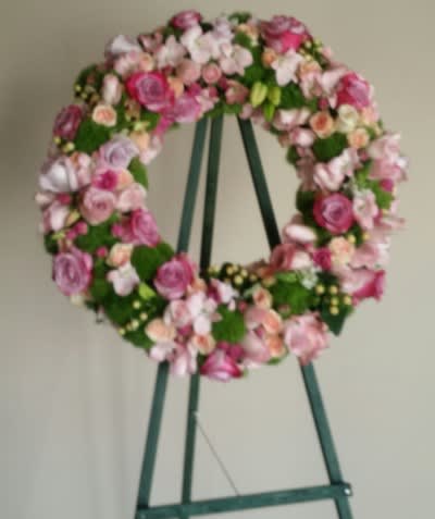Pink and white floral wreath on a green easel