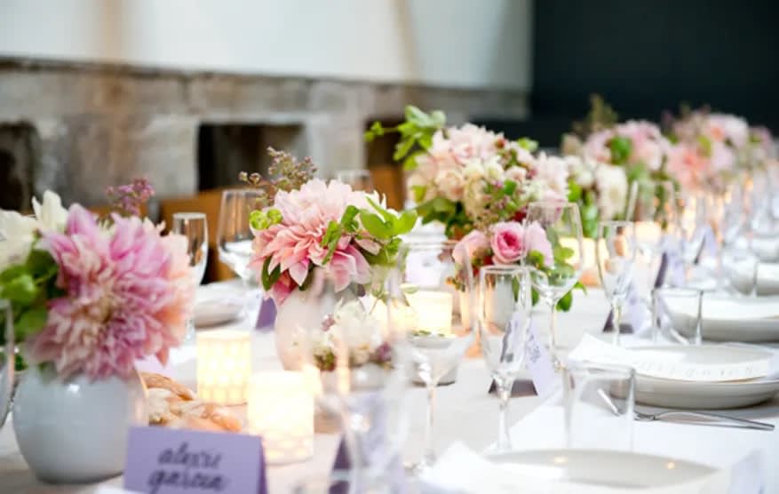 Pink floral centerpieces on a set dining table with candles and glassware