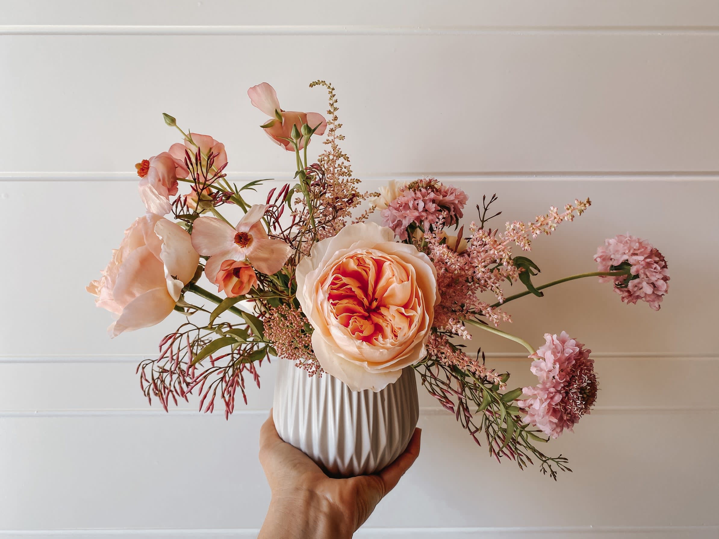 Peach and pink floral arrangement in a white vase