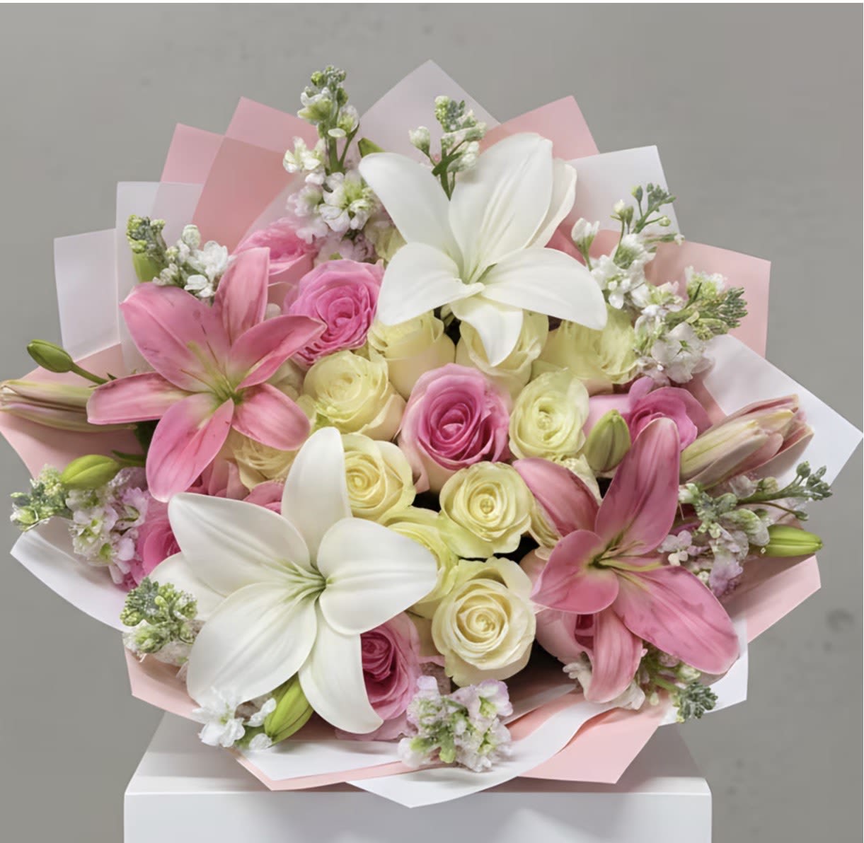Pink and white bouquet with lilies and roses wrapped in pastel paper