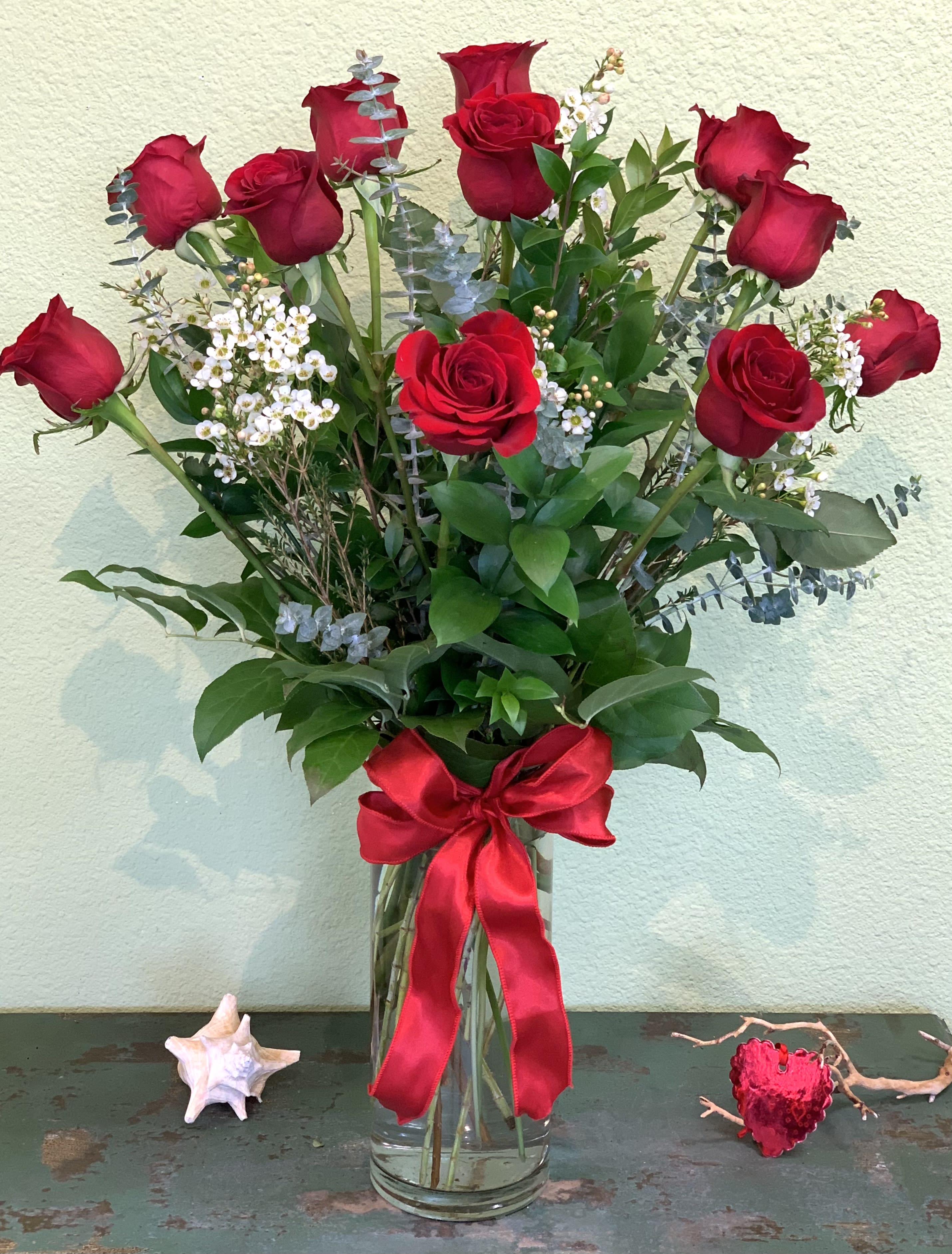 Tall bouquet of red roses in a glass vase with a red ribbon