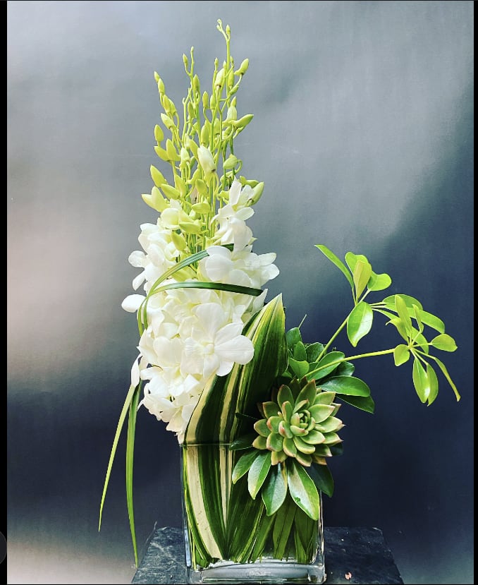 White orchid arrangement with succulents in a glass vase