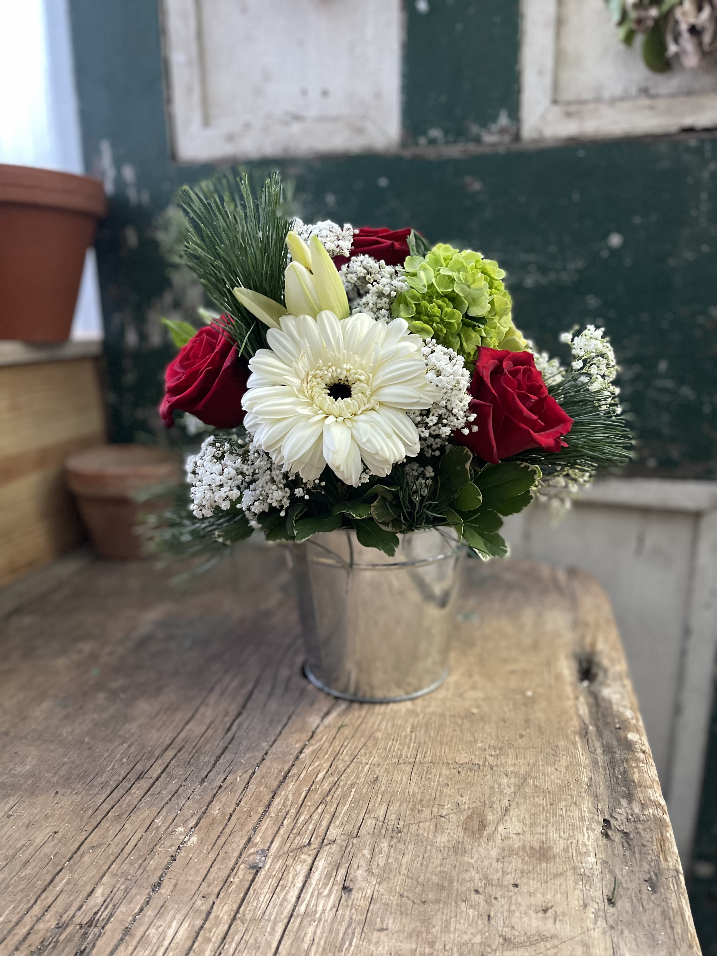 Bouquet of red roses, white gerbera daisy, and green hydrangea in a metal bucket