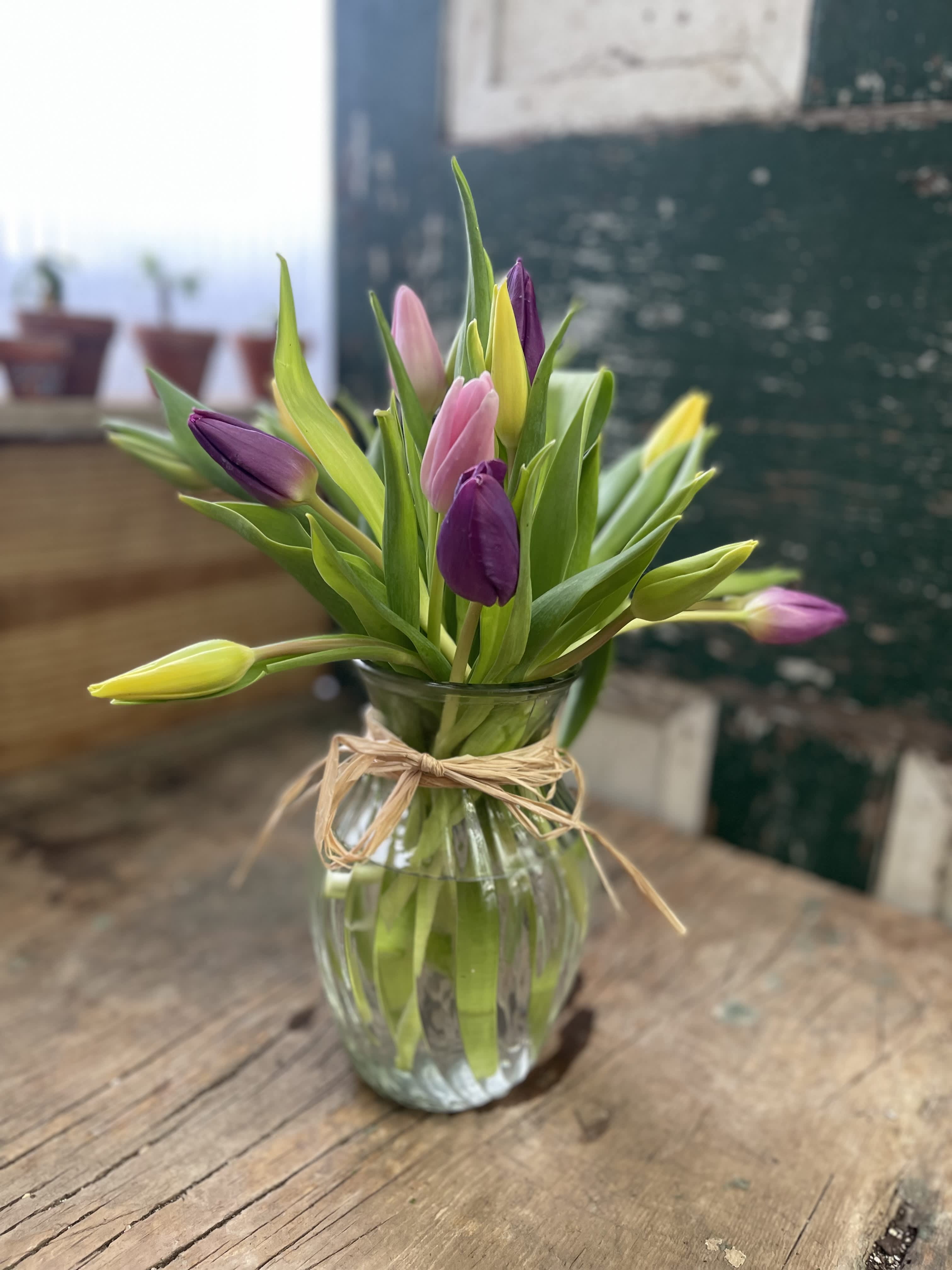Mixed tulips in a clear glass vase tied with twine