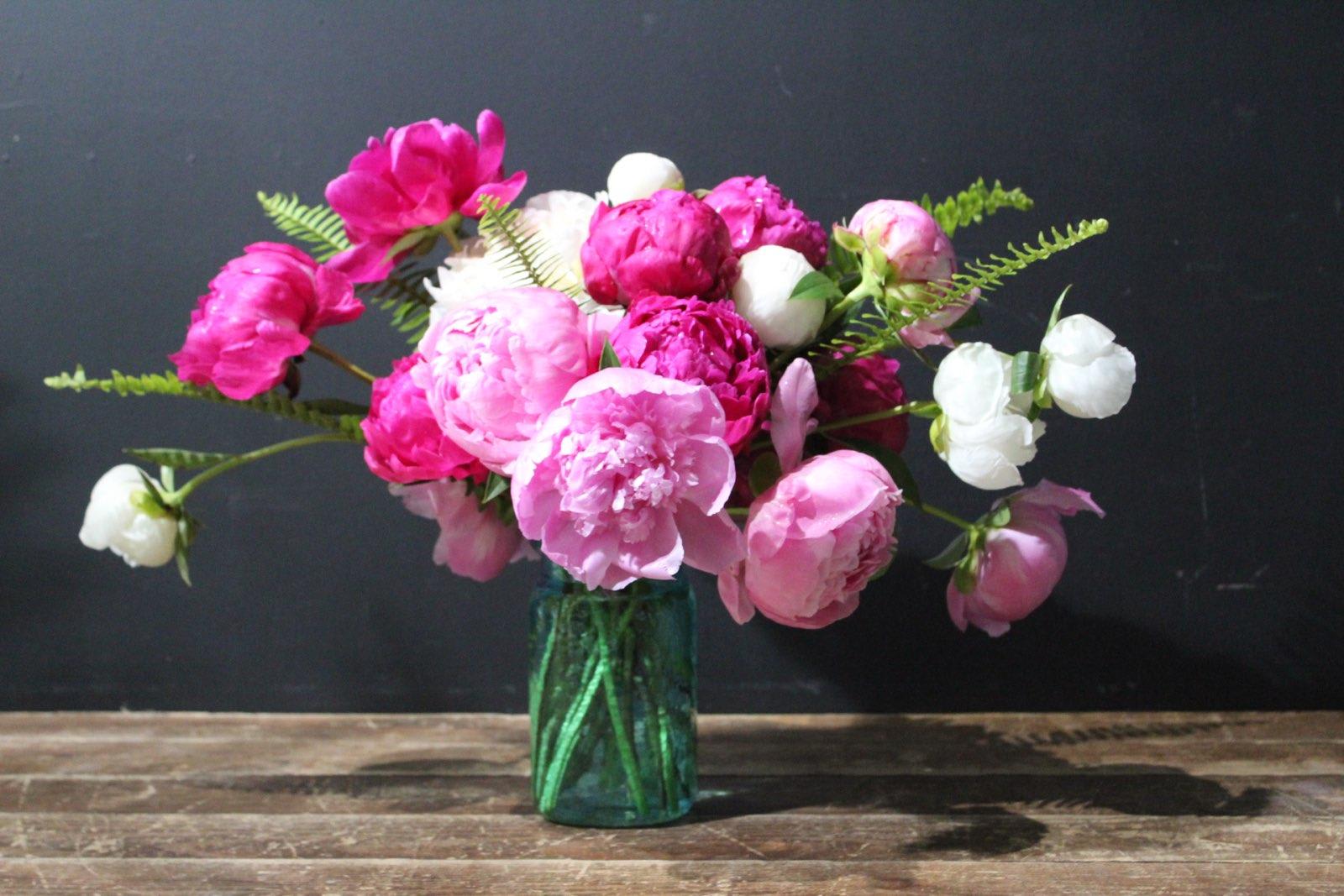 Pink and white peonies in a green glass vase
