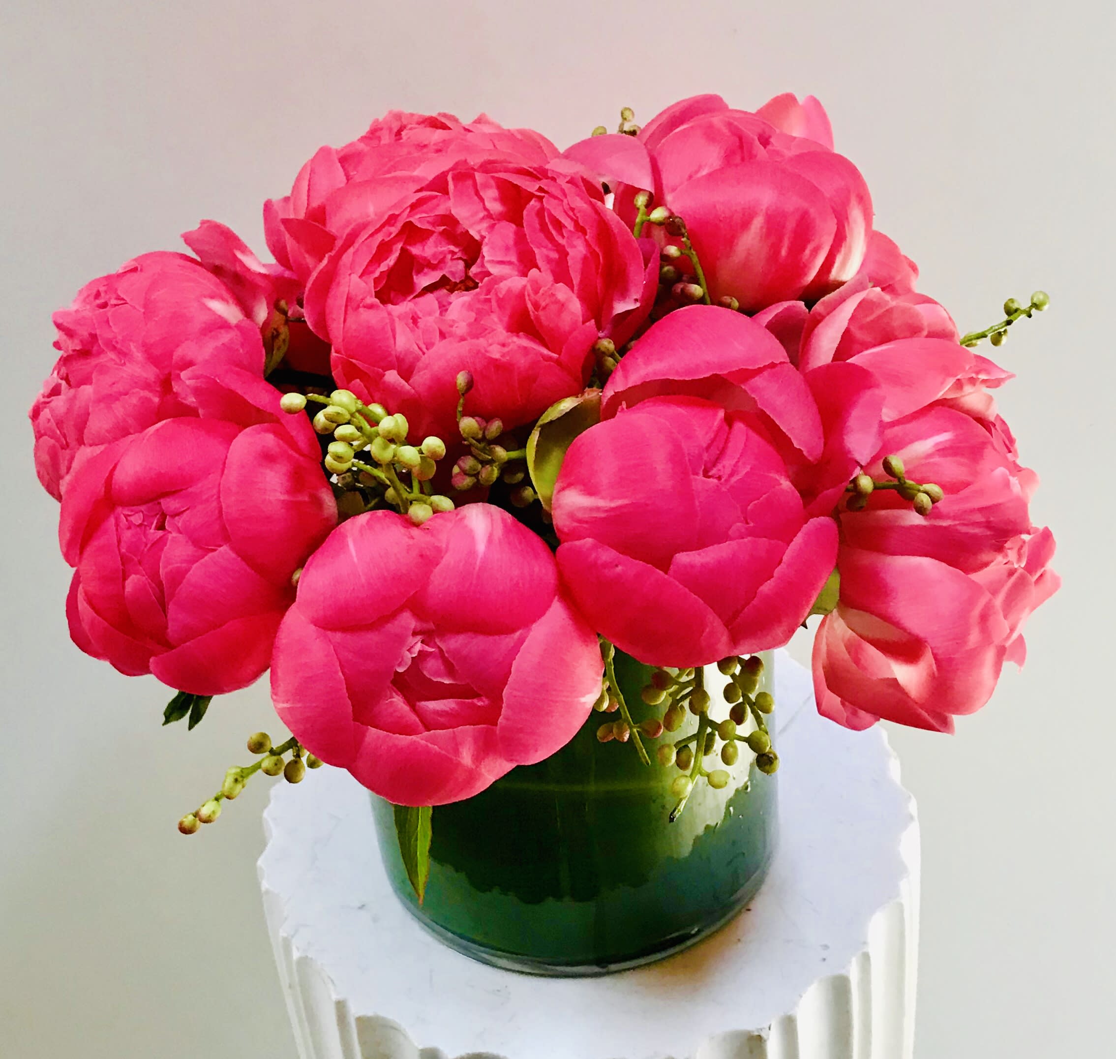 Bright pink peony bouquet in a green glass vase