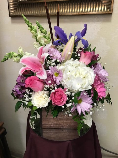Mixed bouquet with pink and white lilies, roses, and purple flowers in a wooden basket