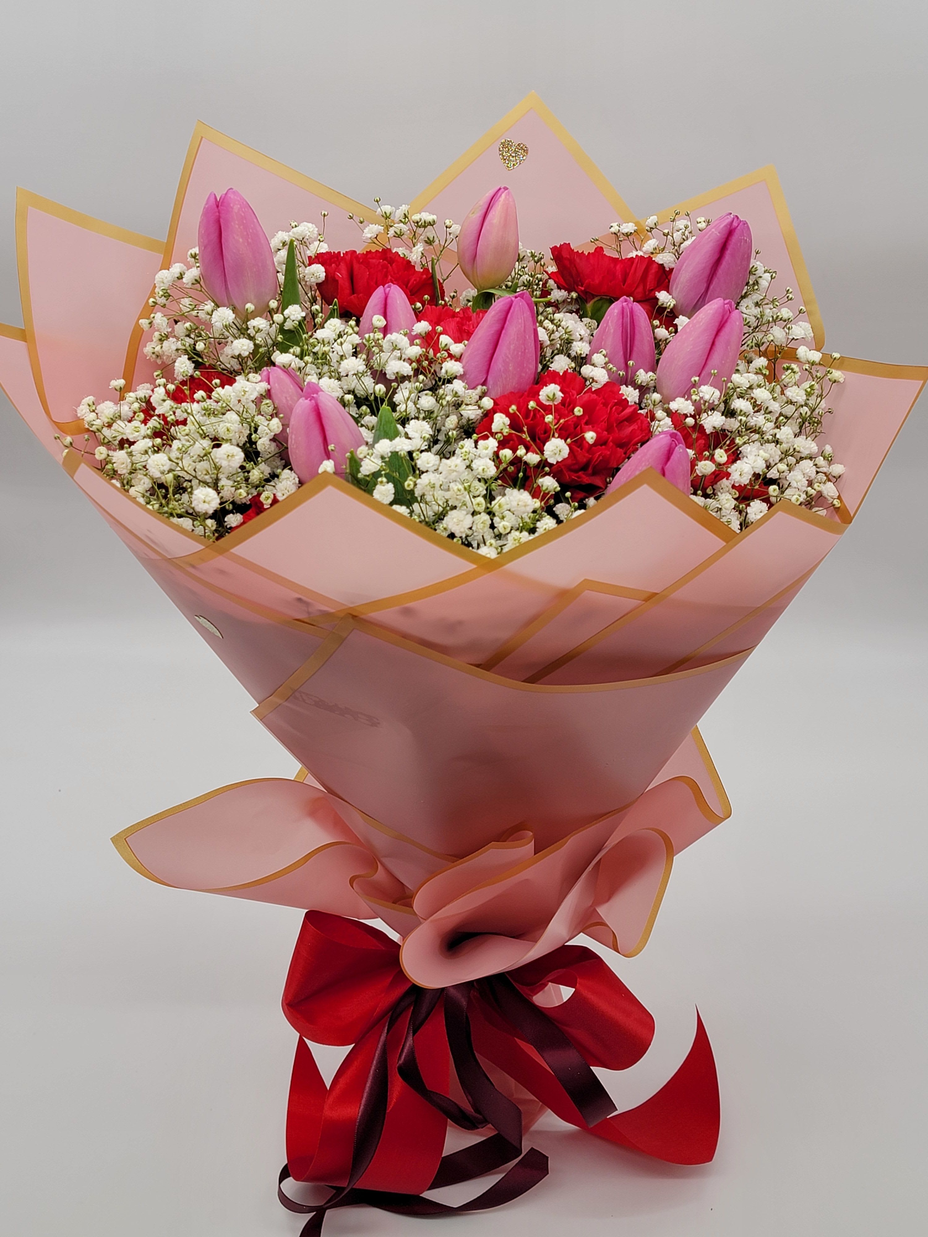 Pink tulips and red carnations in a wrapped bouquet