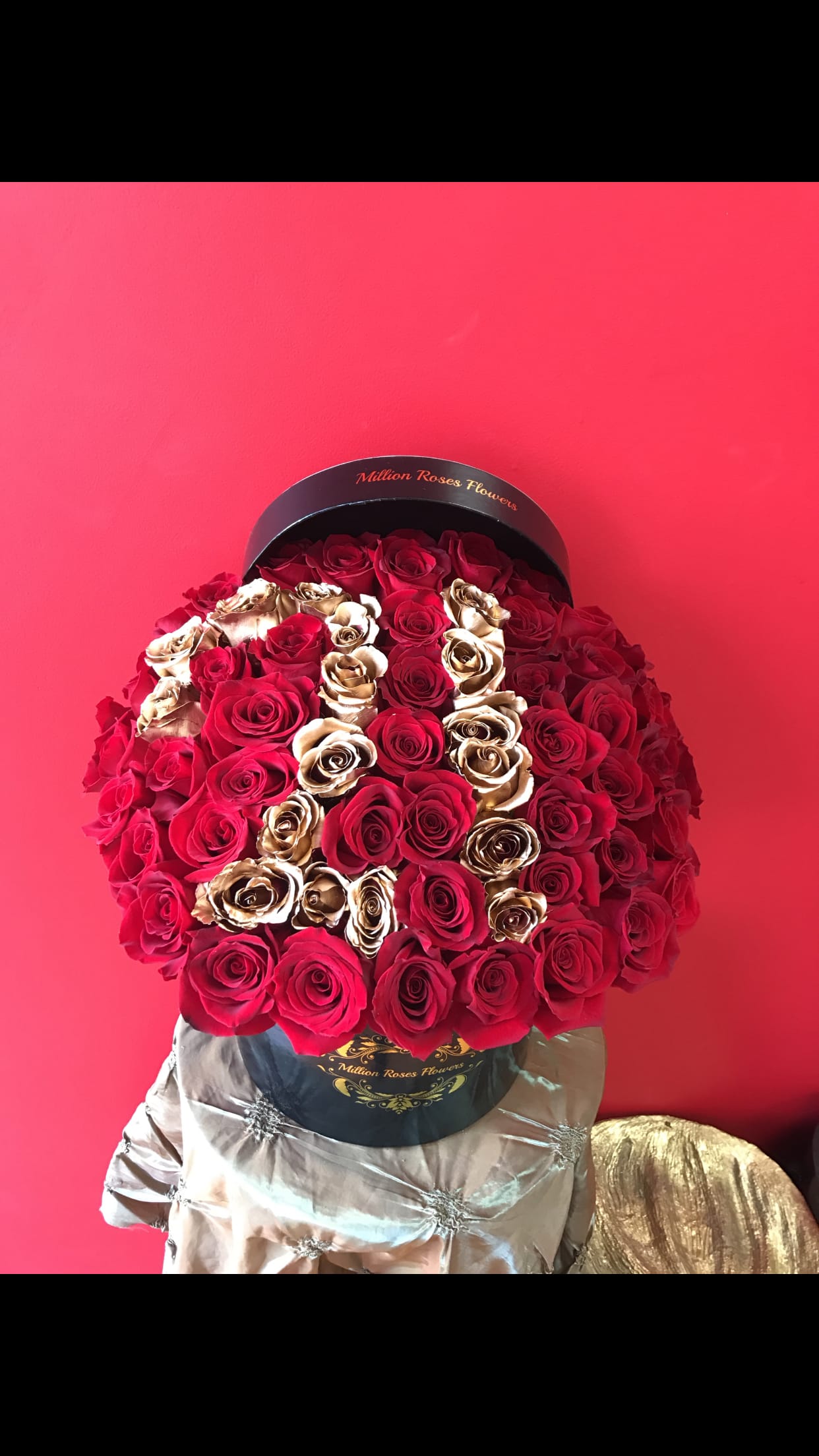 Large bouquet of red and gold roses in a black hatbox