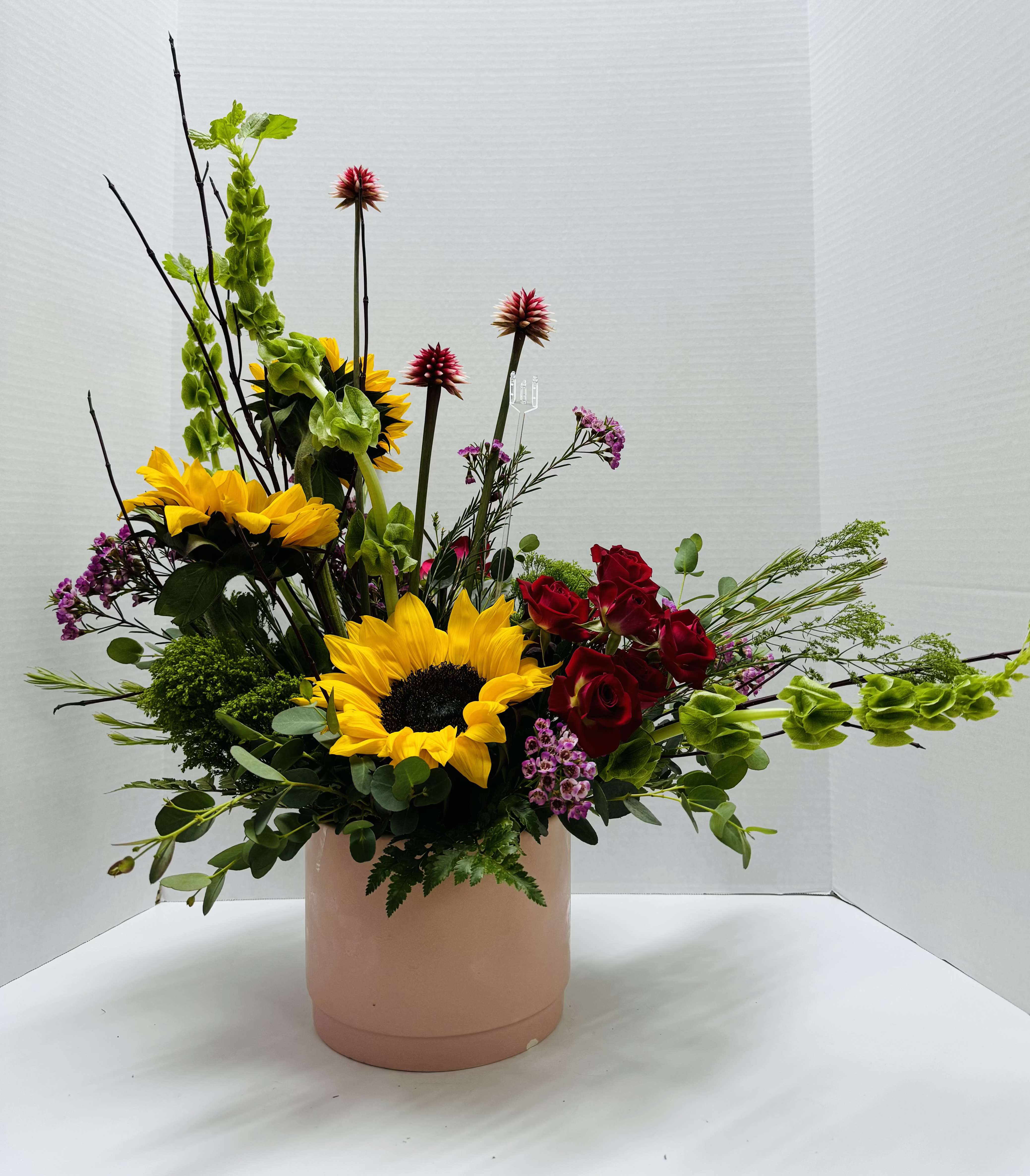 Sunflower and red rose arrangement in a blush cylindrical vase
