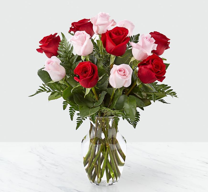 Bouquet of red and pale pink roses in a clear glass vase