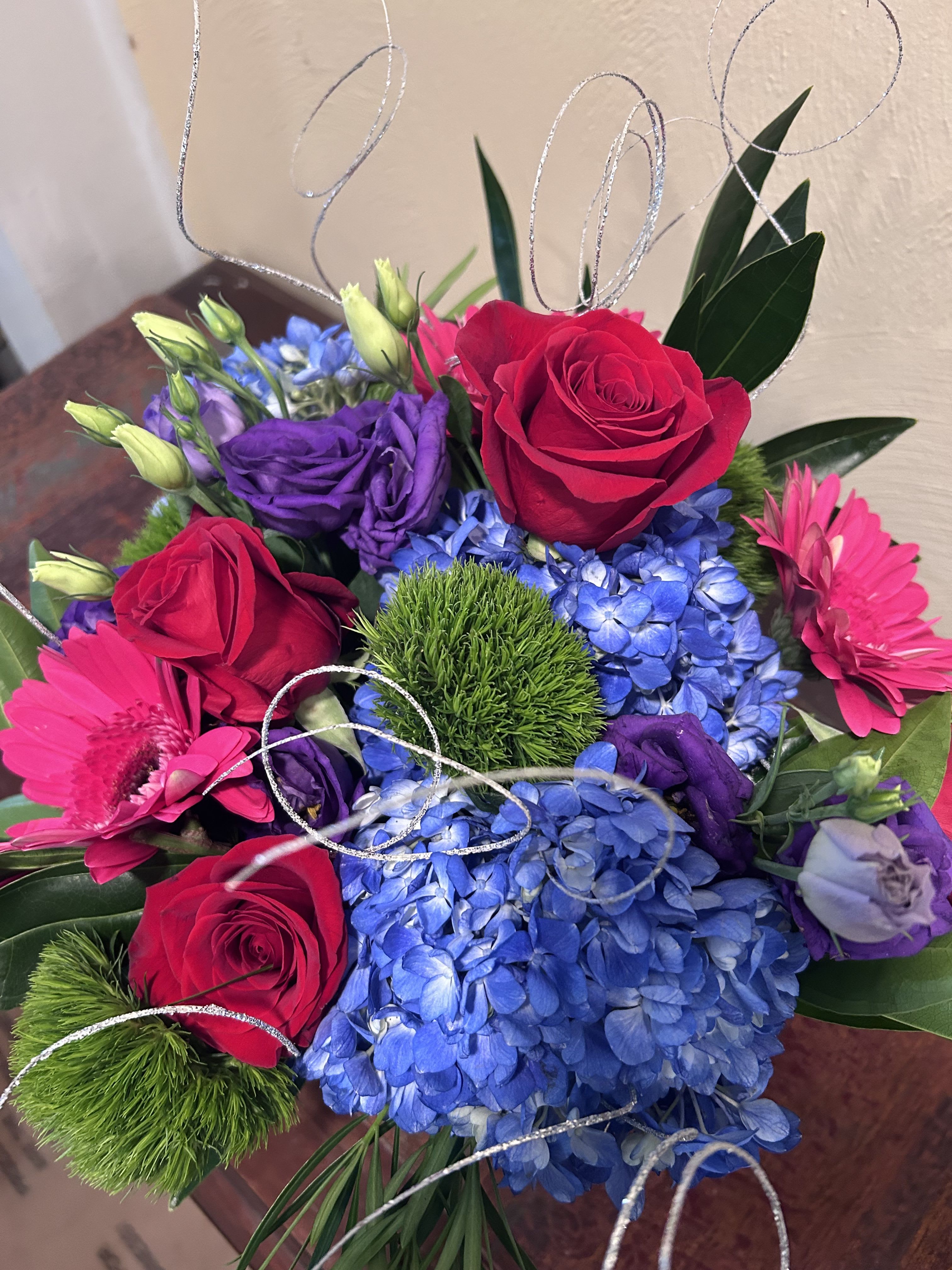 Bouquet of red roses, blue hydrangeas, and pink gerbera daisies