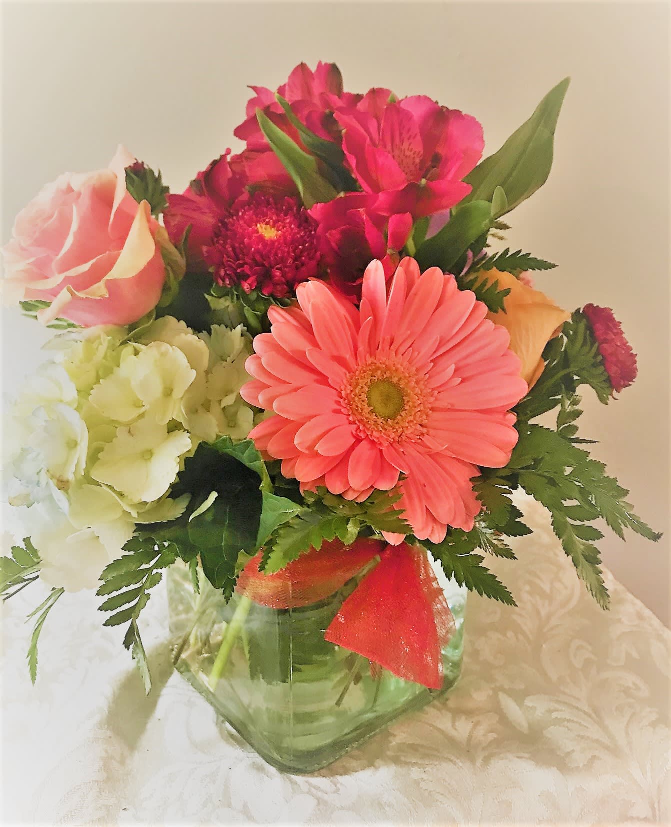 Mixed bouquet in a clear glass vase with pink gerbera daisies and roses