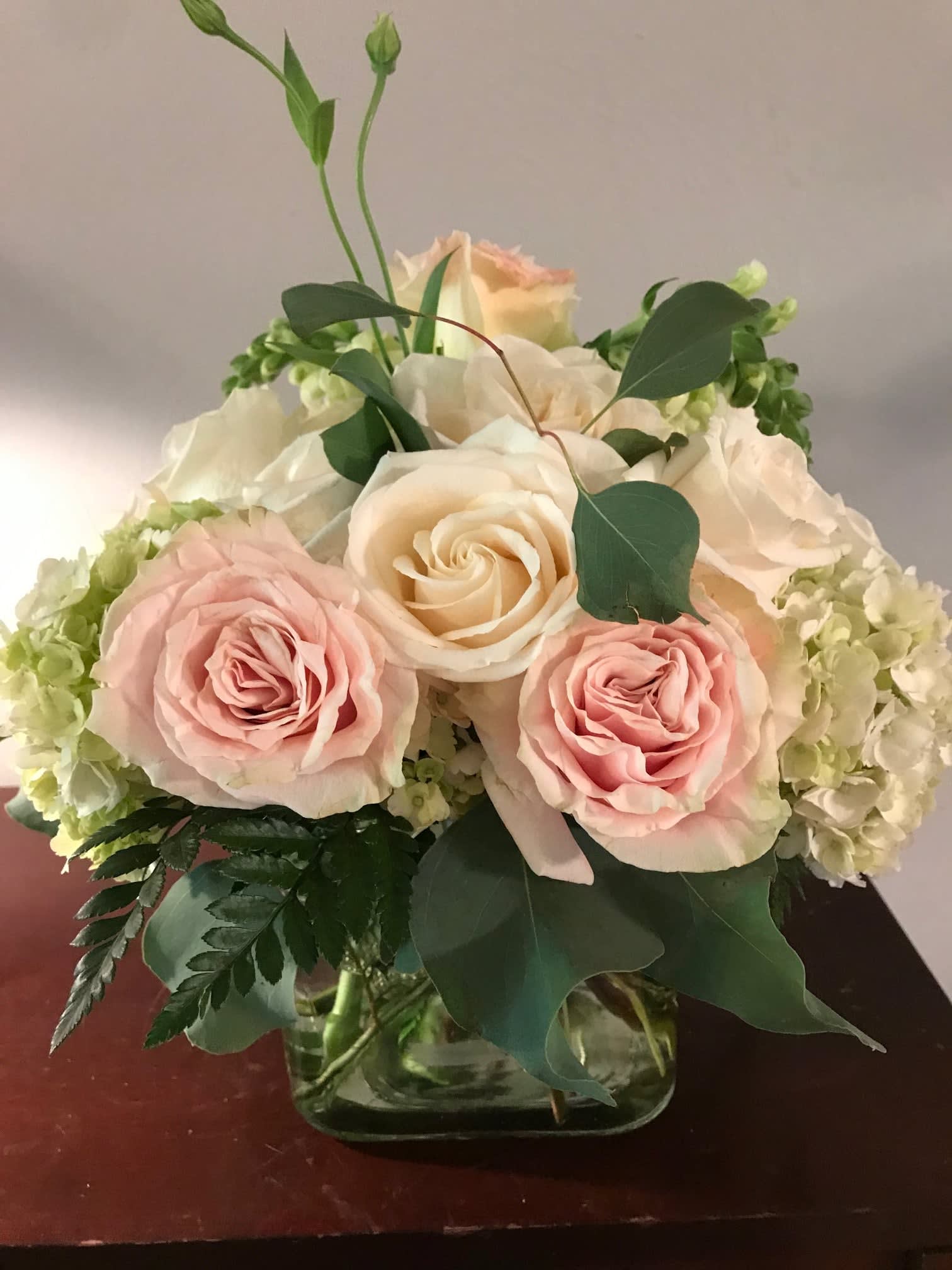 Pink and cream roses arranged in a glass vase