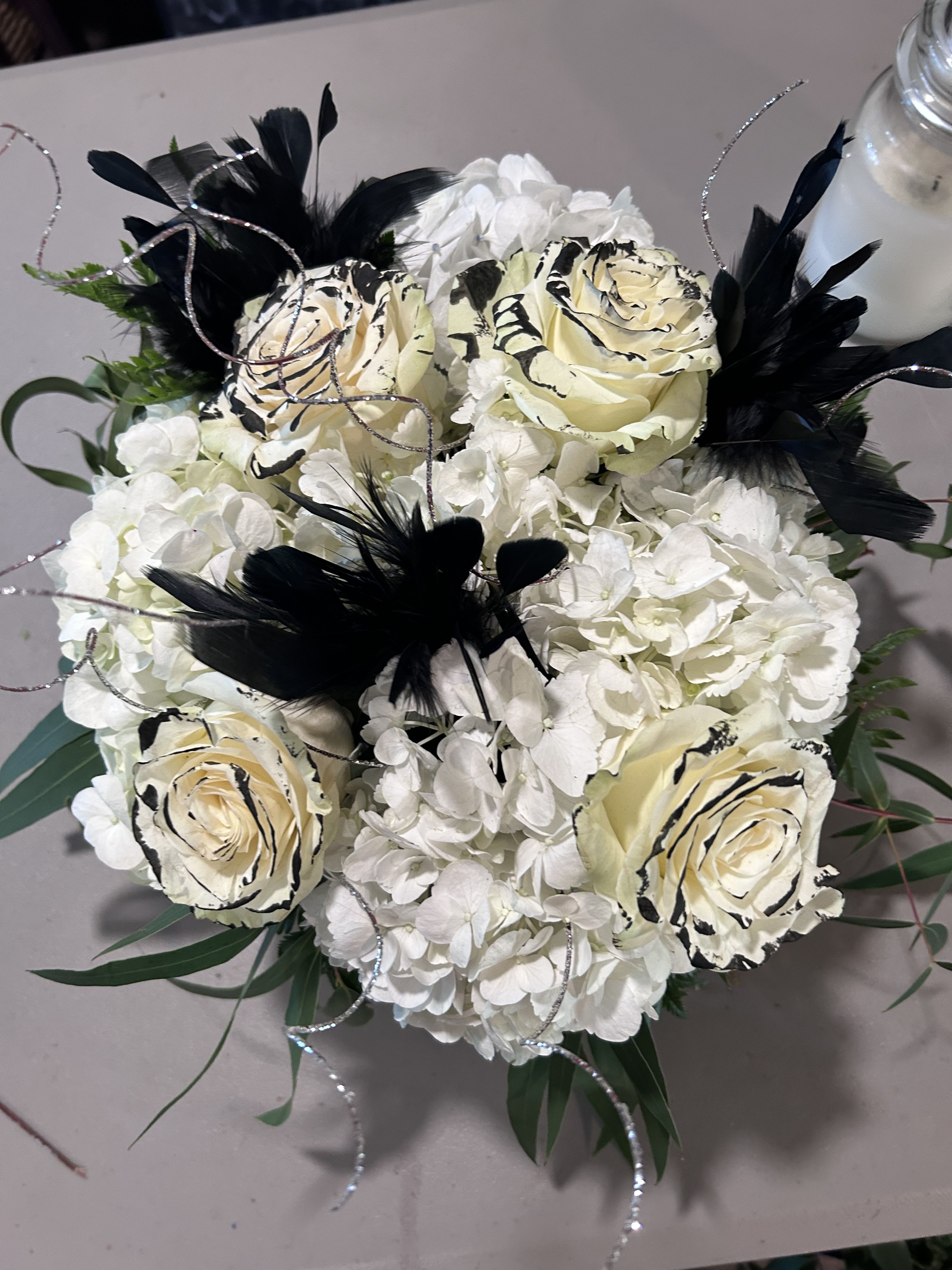 White hydrangea bouquet with cream roses and black feather accents